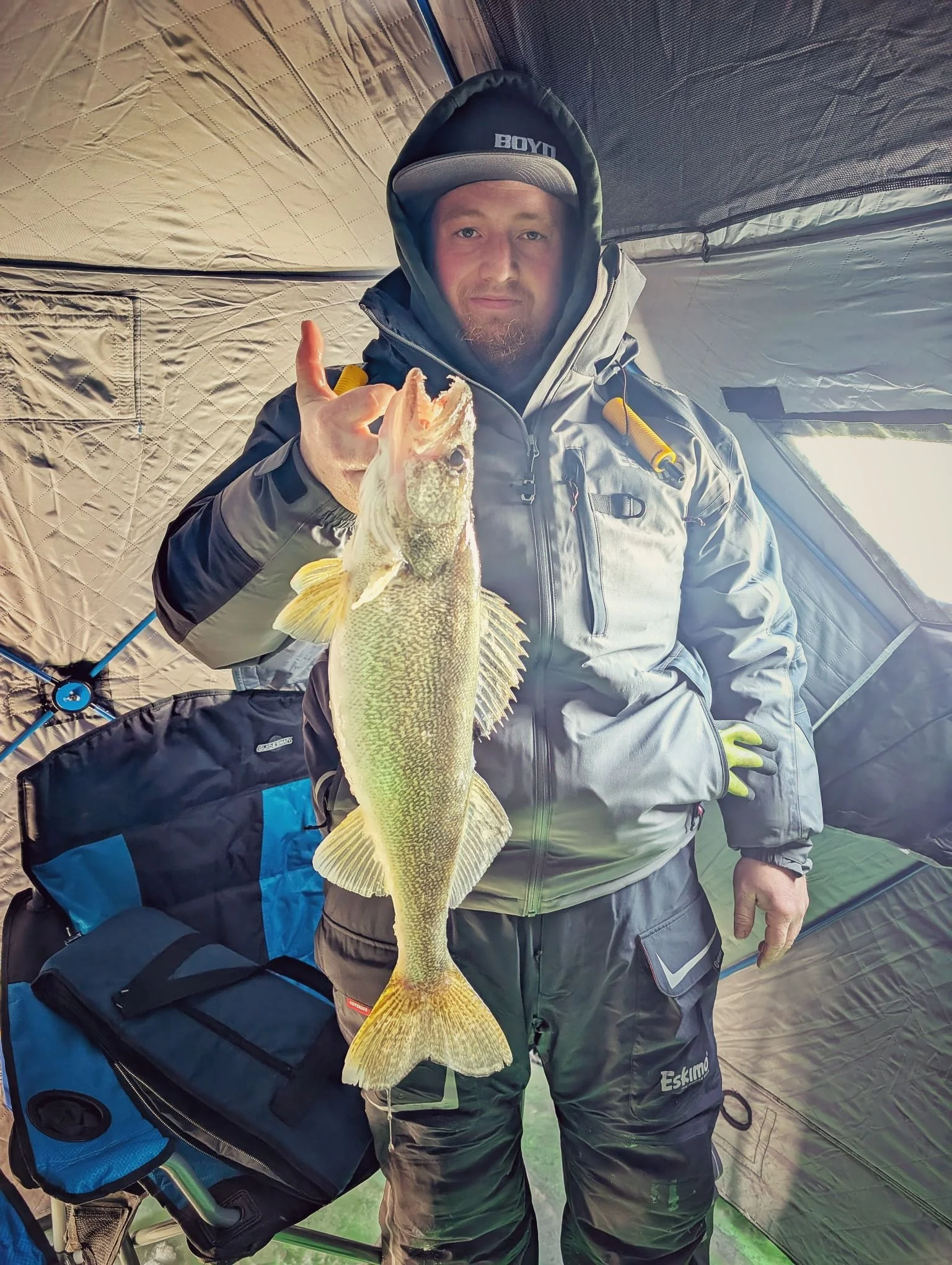  An angler holding a nice Saginaw Bay walleye inside a spacious, insulated ice fishing shanty during a guided winter trip with Reel Fish'n.   