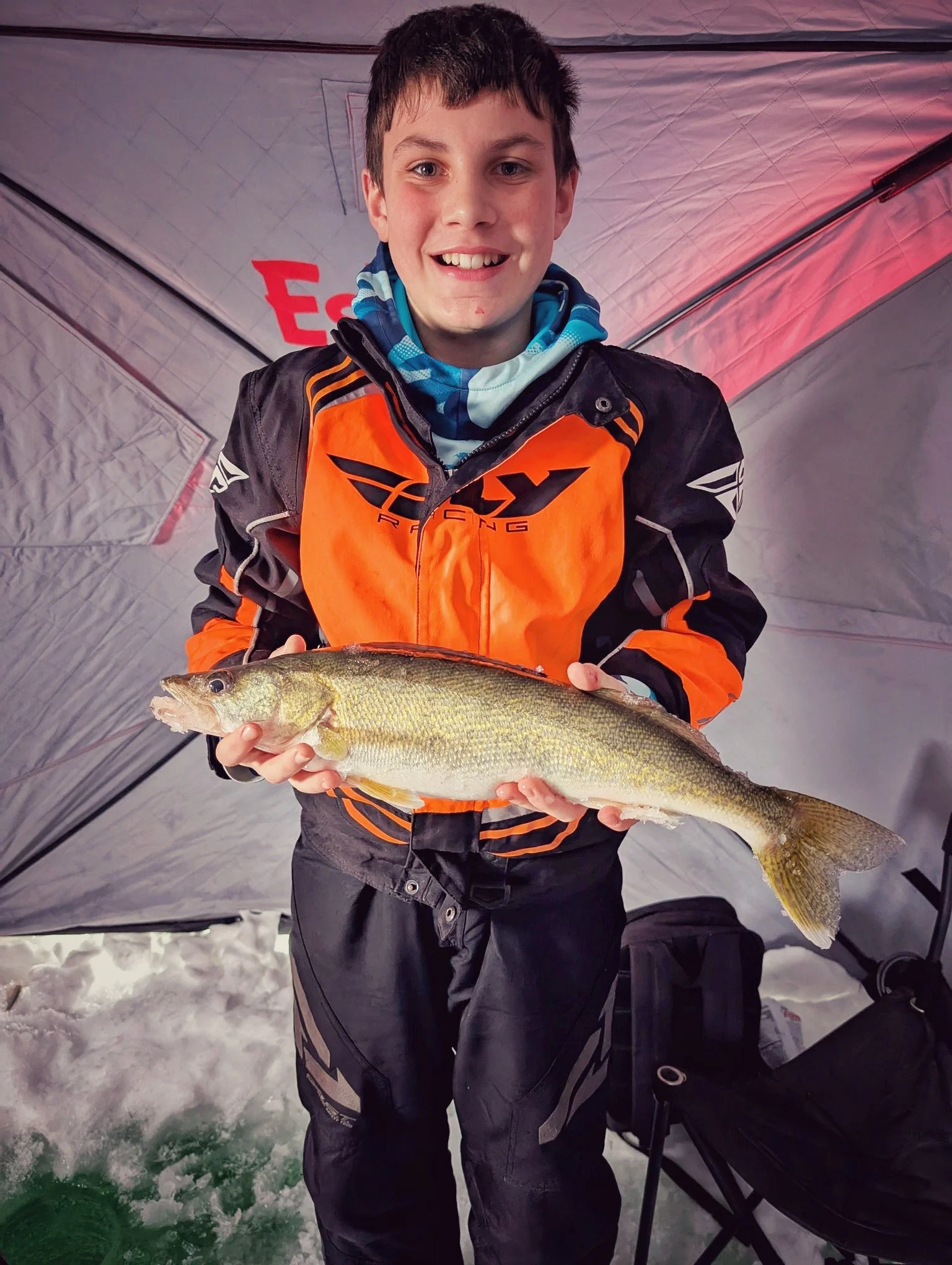  A young angler holding a Saginaw Bay walleye caught during a family-friendly ice fishing charter with Reel Fish'n.   