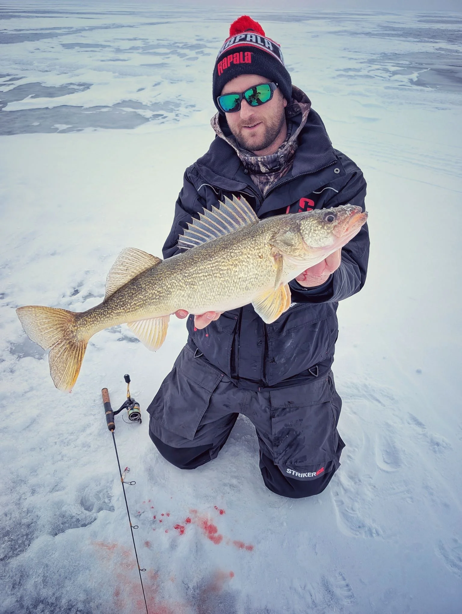  A successful angler showcasing a beautiful winter walleye caught on the frozen waters of Saginaw Bay during a Reel Fish'n ice fishing excursion.   