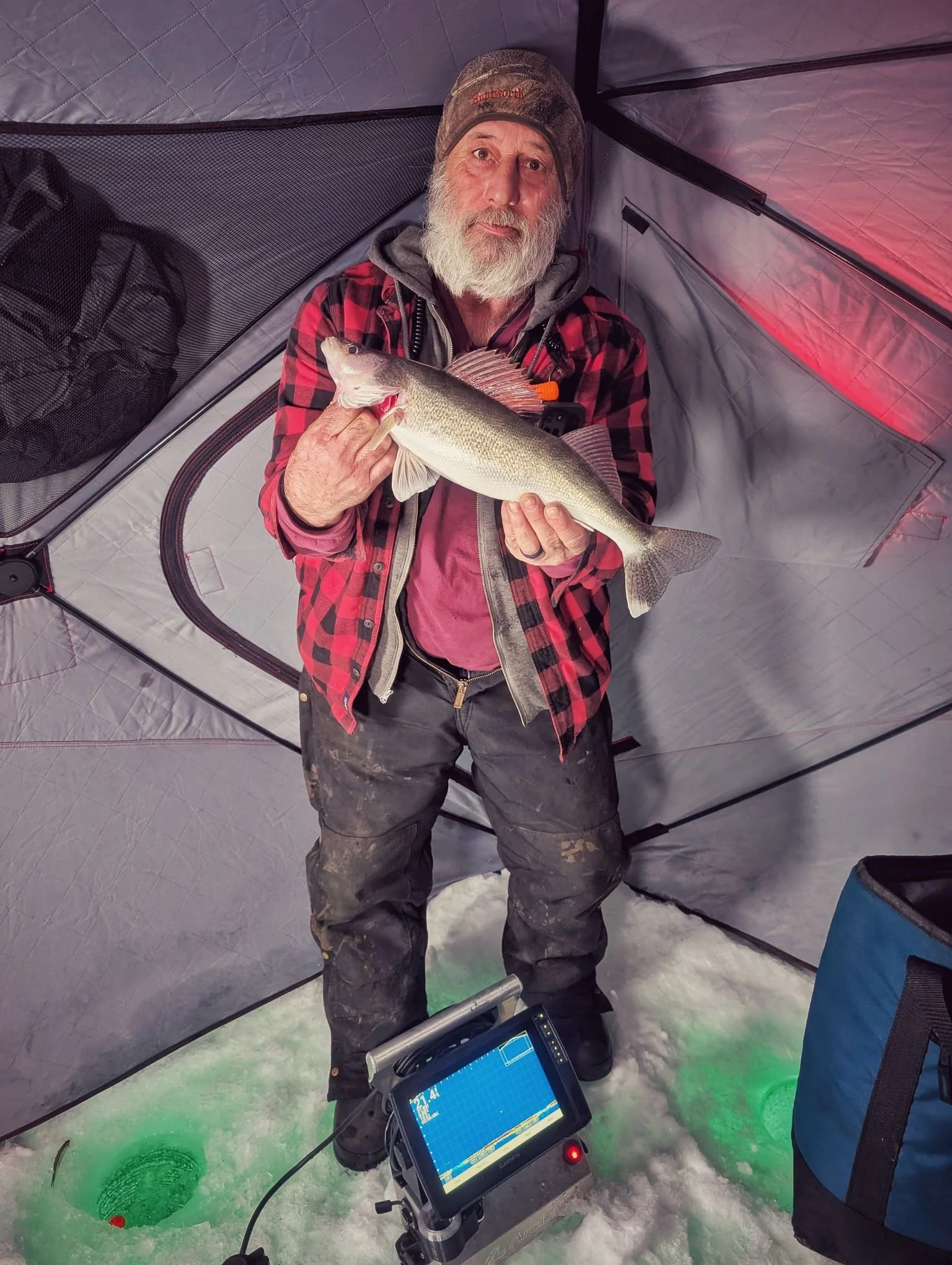  An angler holding a Saginaw Bay walleye while using live sonar electronics inside a comfortable hub-style shanty with Reel Fish'n.   