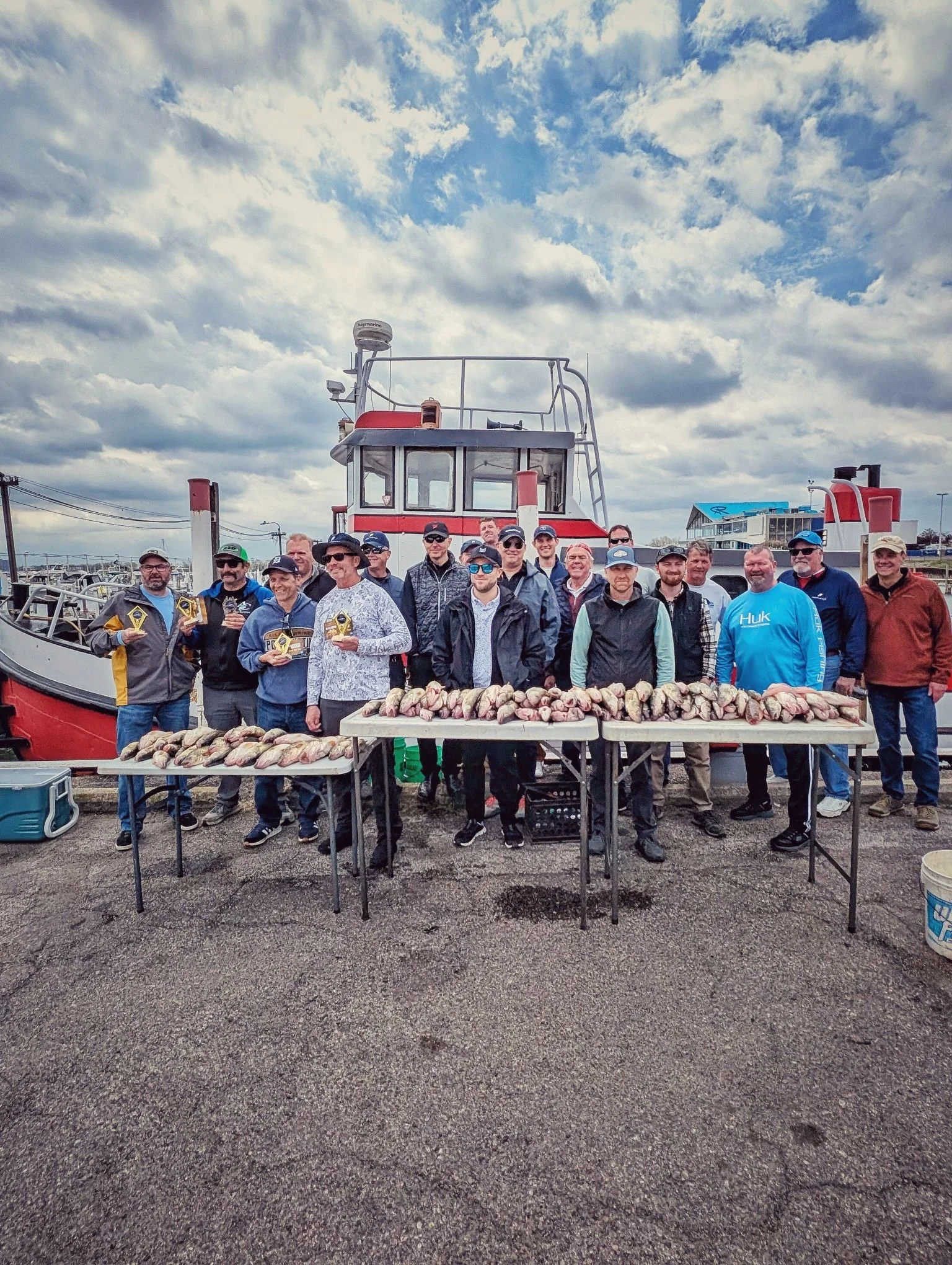  A 12-person corporate fishing party standing with their catch in front of the charter fleet at a Detroit River marina. 