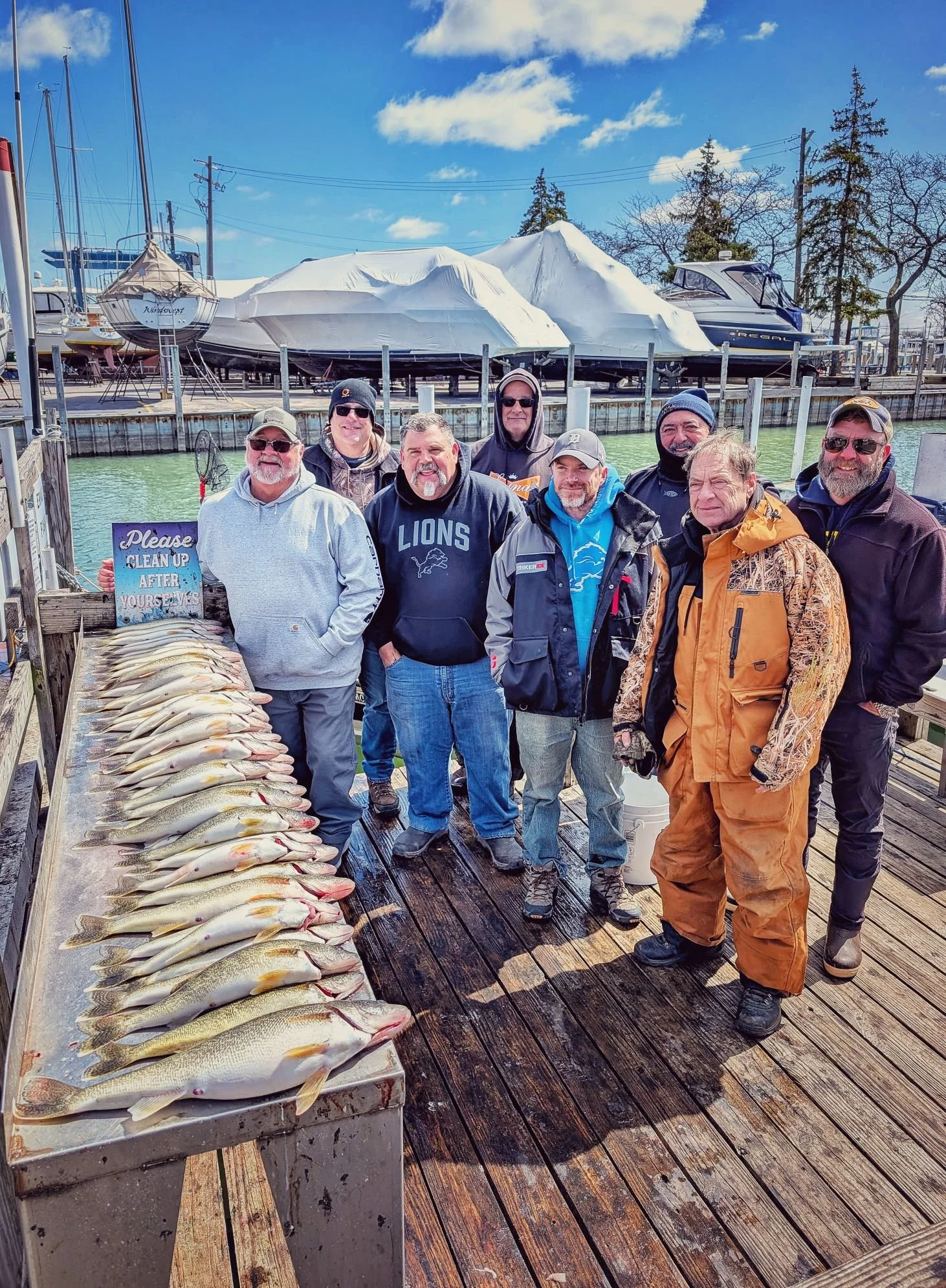  A multi-boat corporate fishing party displaying a heavy limit of spring walleye on the dock after a Detroit River jigging trip. 