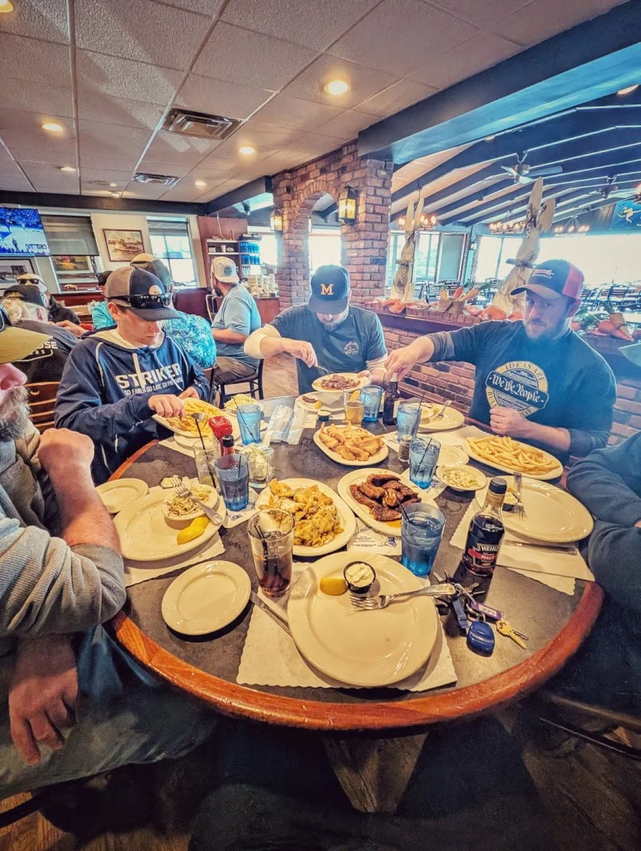  A group of anglers sitting around a table enjoying a fresh walleye fish fry at a local restaurant after their Reel Fish'n charter. 