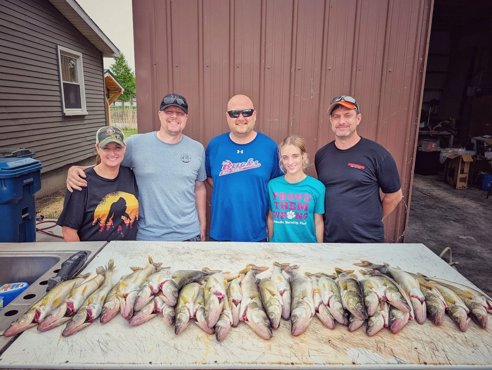  A family of five posing behind a full limit of walleye at a Saginaw Bay cleaning station after a successful day on the water.   