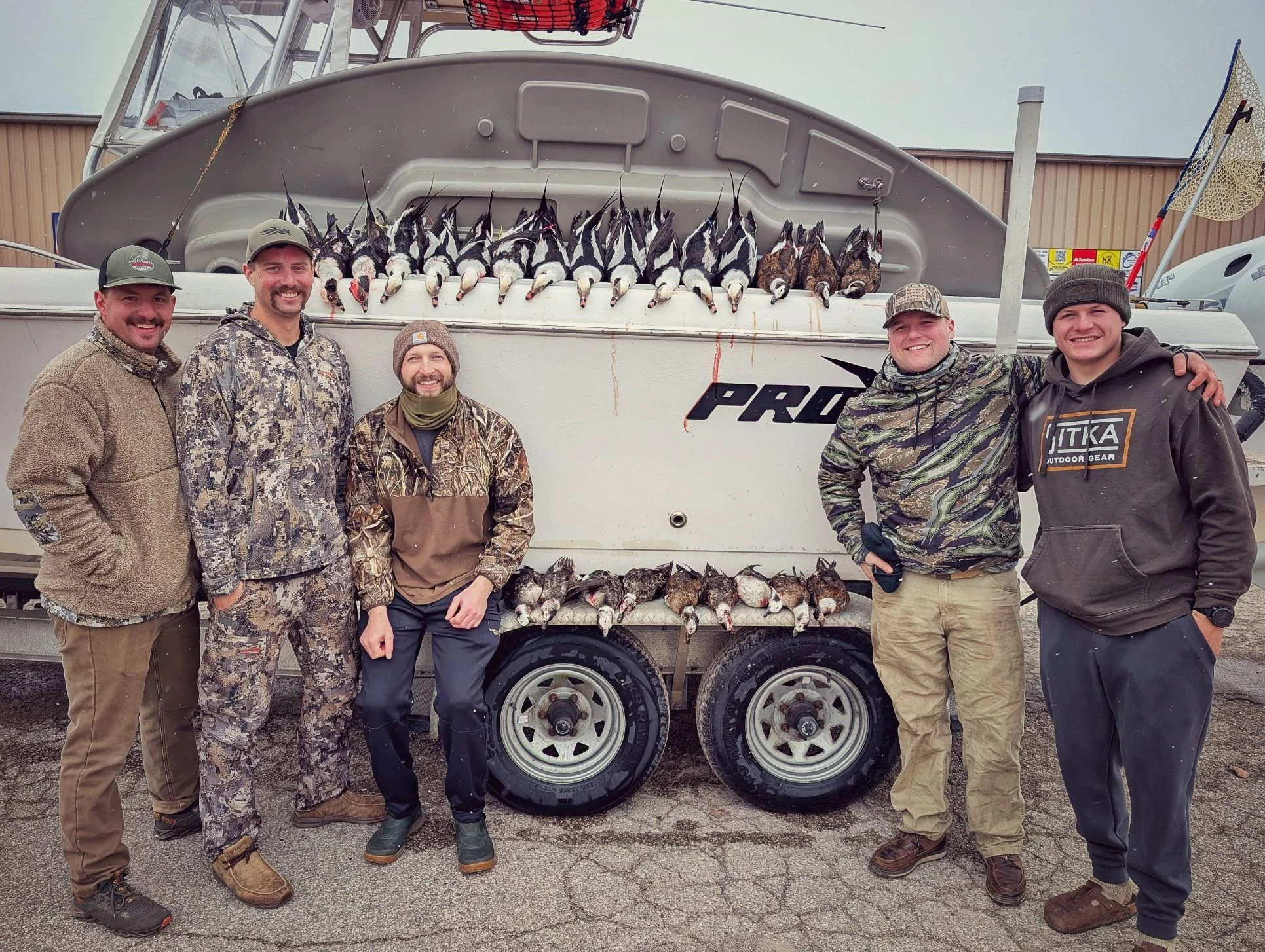  Five hunters standing with their harvest after a coordinated open-water layout duck hunt on Saginaw Bay with Reel Fish'n LLC.   