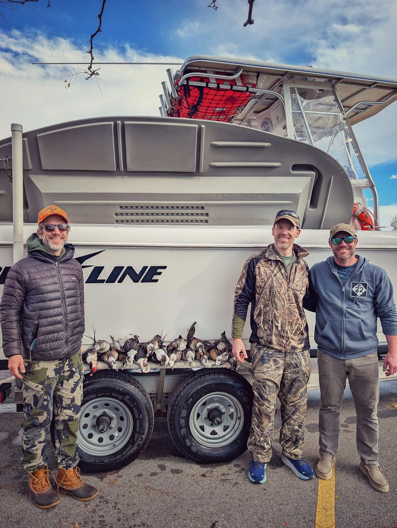Three successful hunters displaying a full limit of Saginaw Bay sea ducks after an open-water layout hunt with Reel Fish'n.
