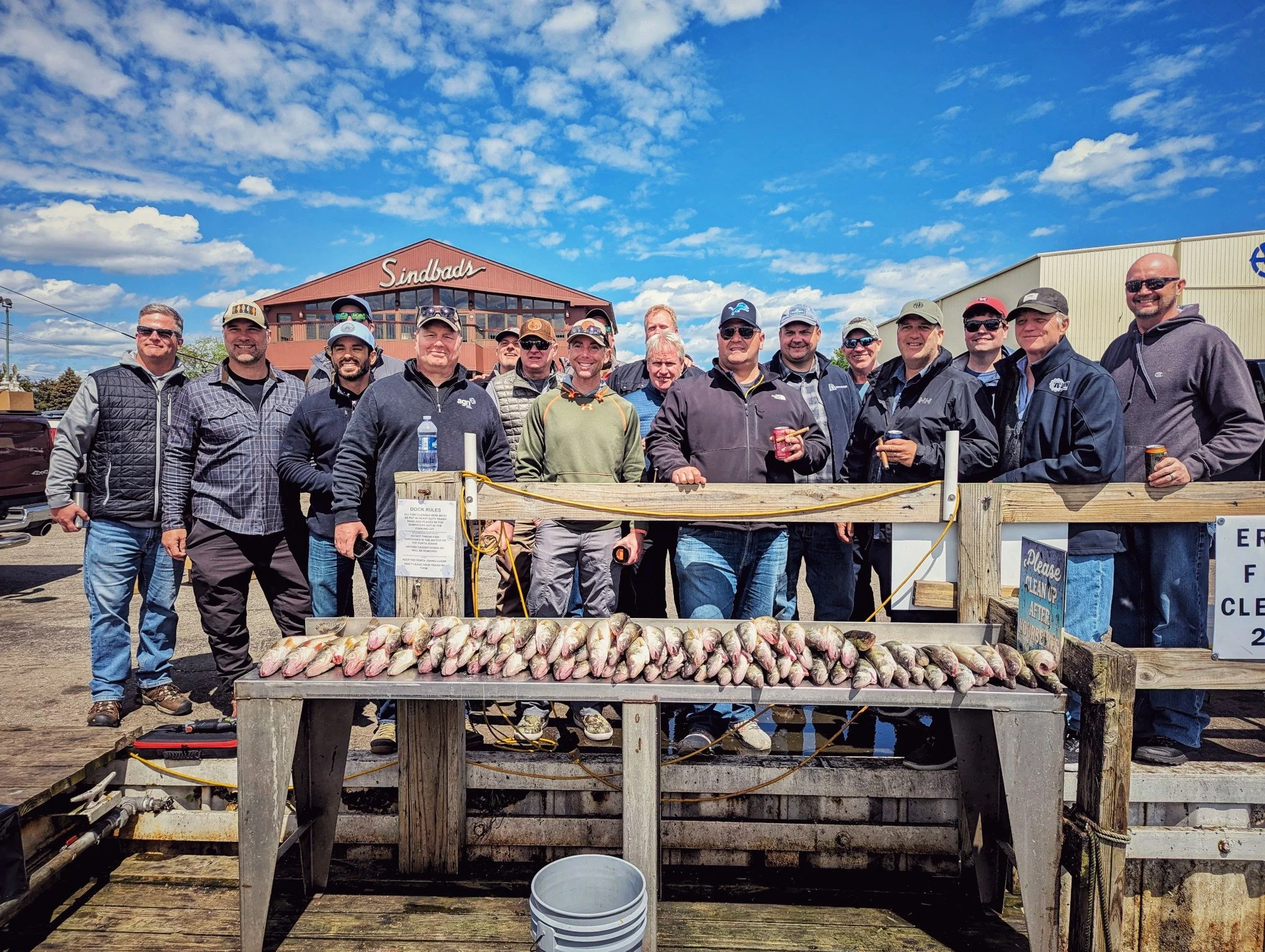 A corporate fishing party displaying a massive walleye harvest at a Detroit River marina.