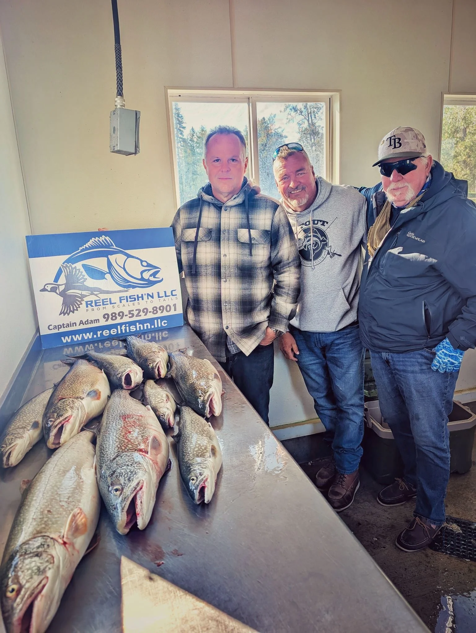 Proud anglers displaying their Lake Trout catch at the cleaning station after a successful day of trolling the DeTour Passage with Reel Fish'n.