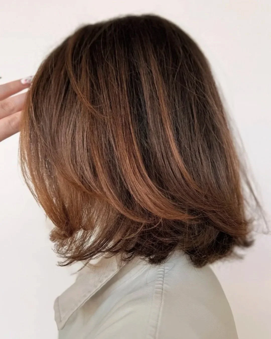 Layered shoulder-length light brown hair with reddish highlights, demi-permanent color and gray blending