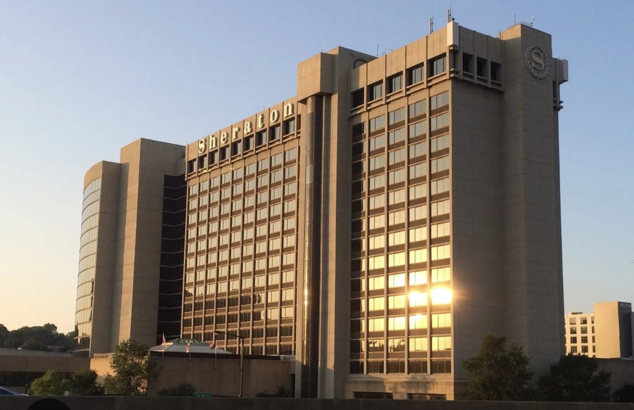 Tall Sheraton hotel building with reflective windows during sunset.