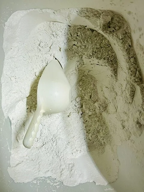 A scoop partially buried in white powder, likely flour, inside a box or container.