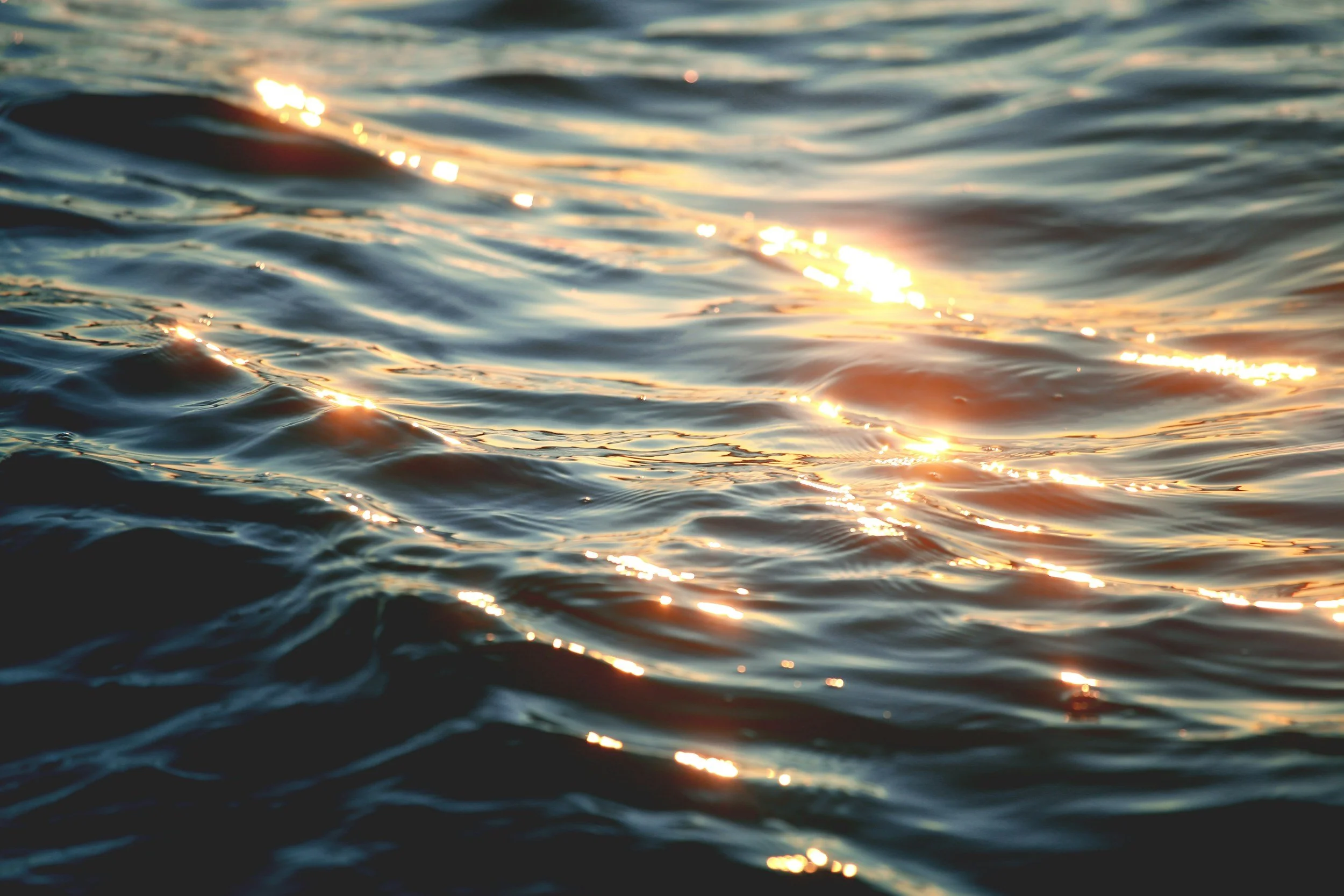 Close-up of a body of water with small waves and sunlight reflecting on the surface.