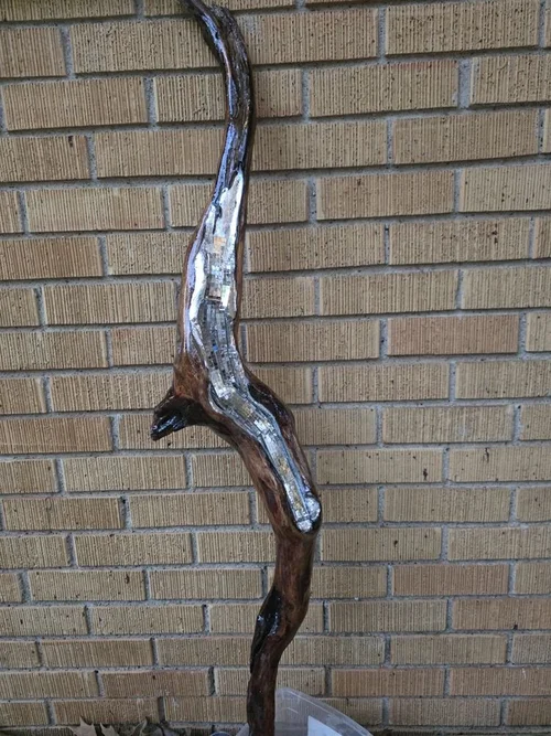 Silver driftwood sculpture against brick