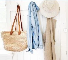 Beach bag, blue towel, straw hat, and beige cloth hanging on hooks