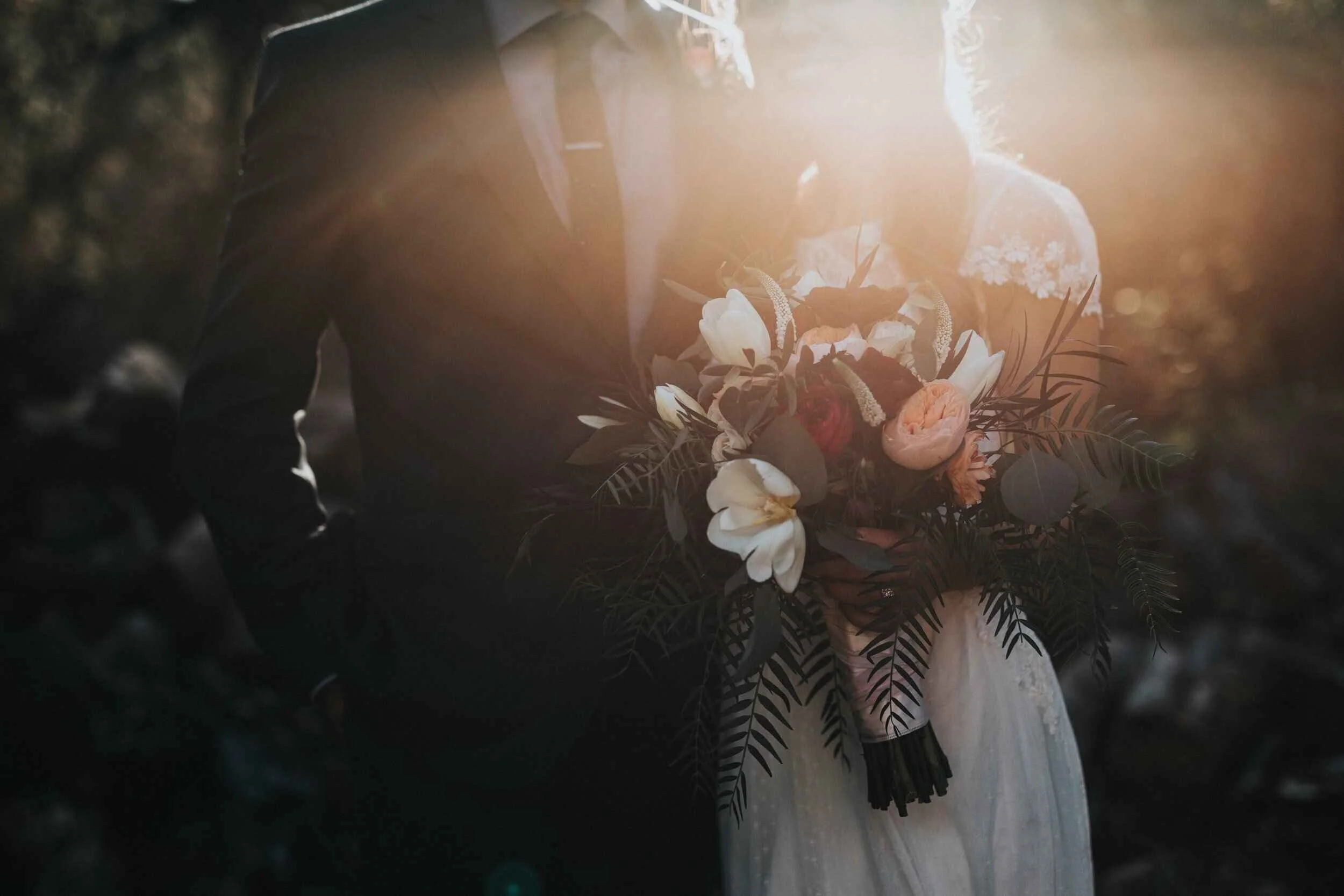Bride and groom holding each other with colourful flower bouquet.