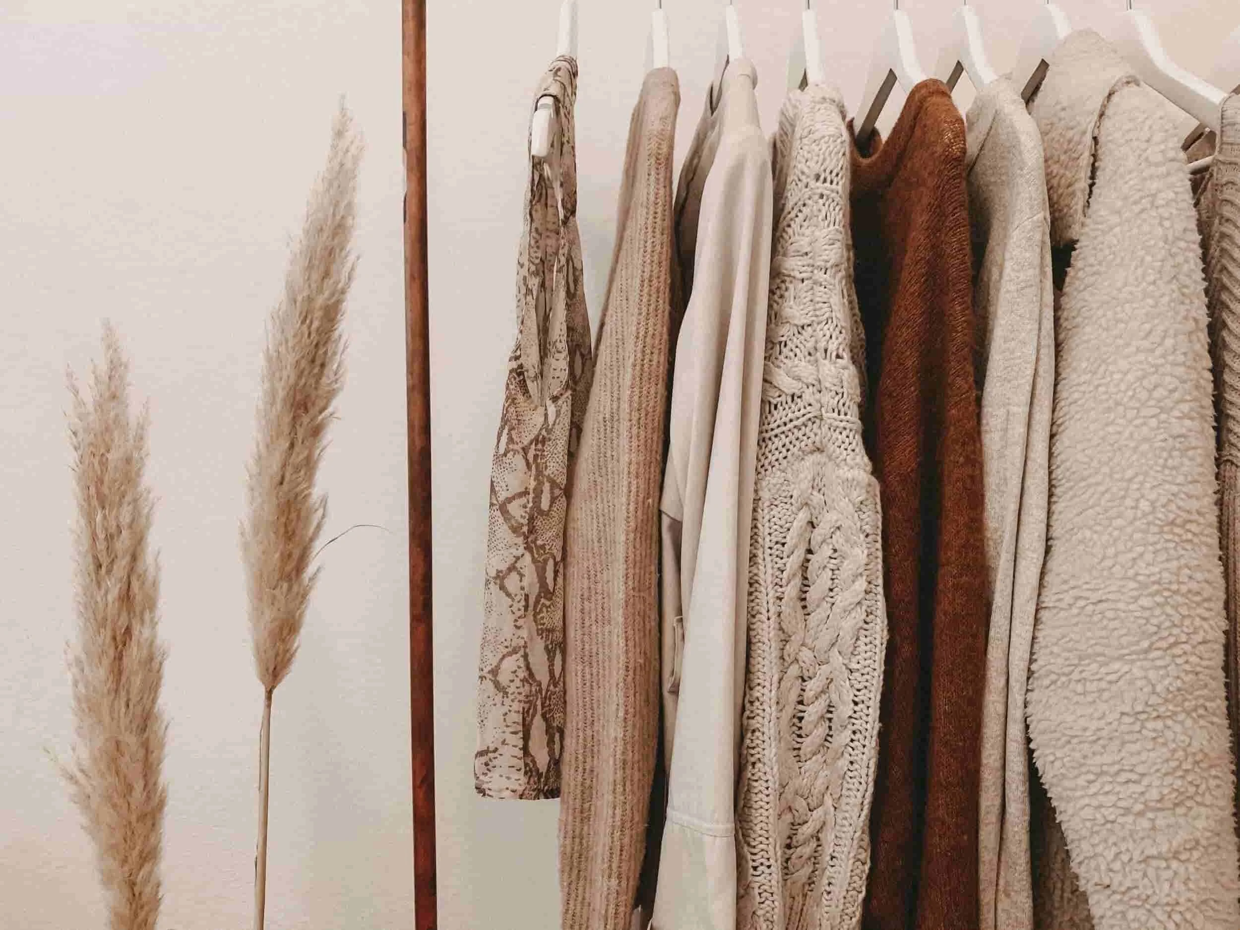 womens capsule wardrobe on a rack in neutral colours.