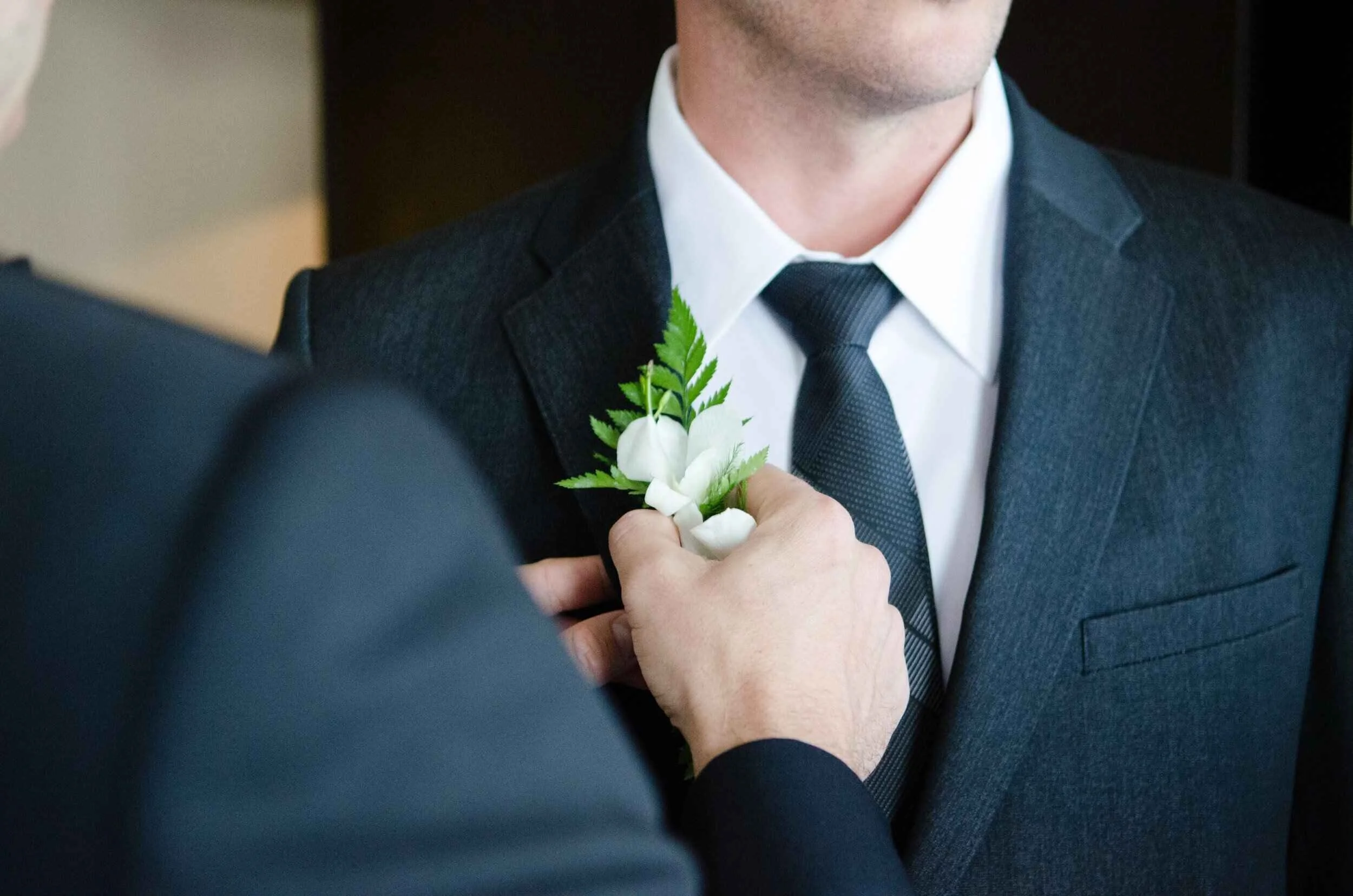 groomsmen in black and white suit, with flower pin.