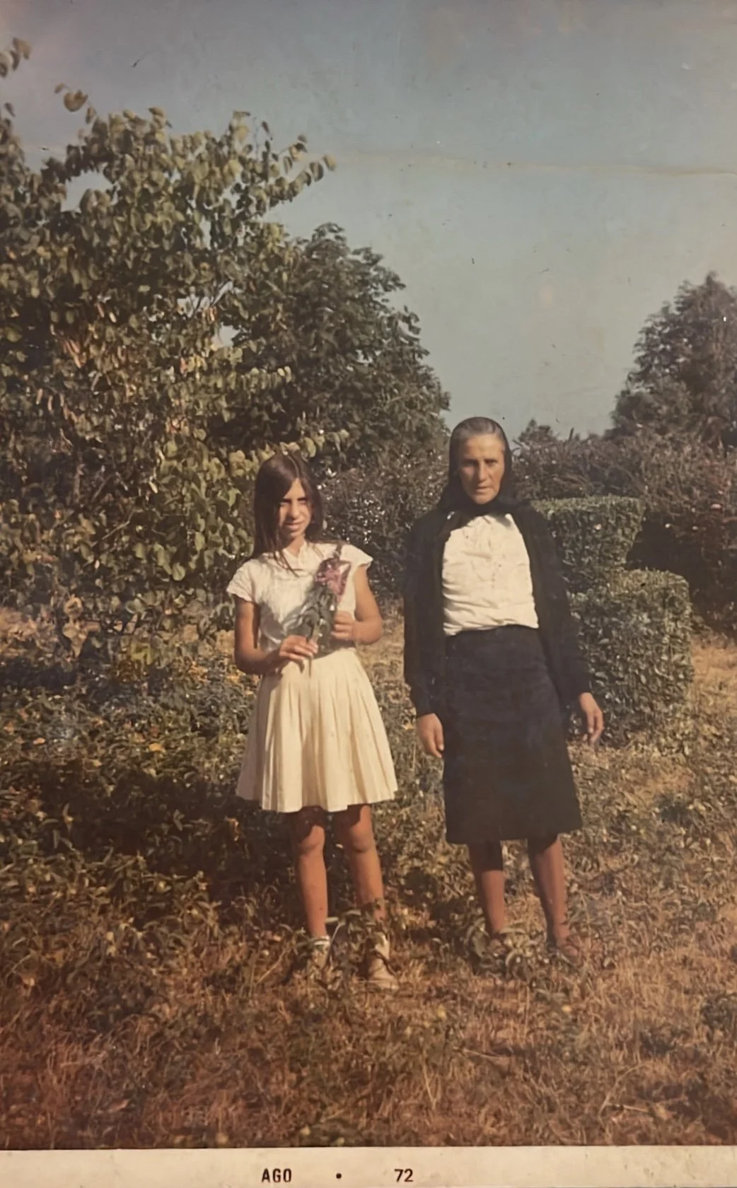 Family archive photograph of two generations standing in a garden in Portugal.