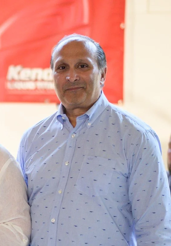 Mies sinisessä kauluspaidassa hymyilee kameraan.