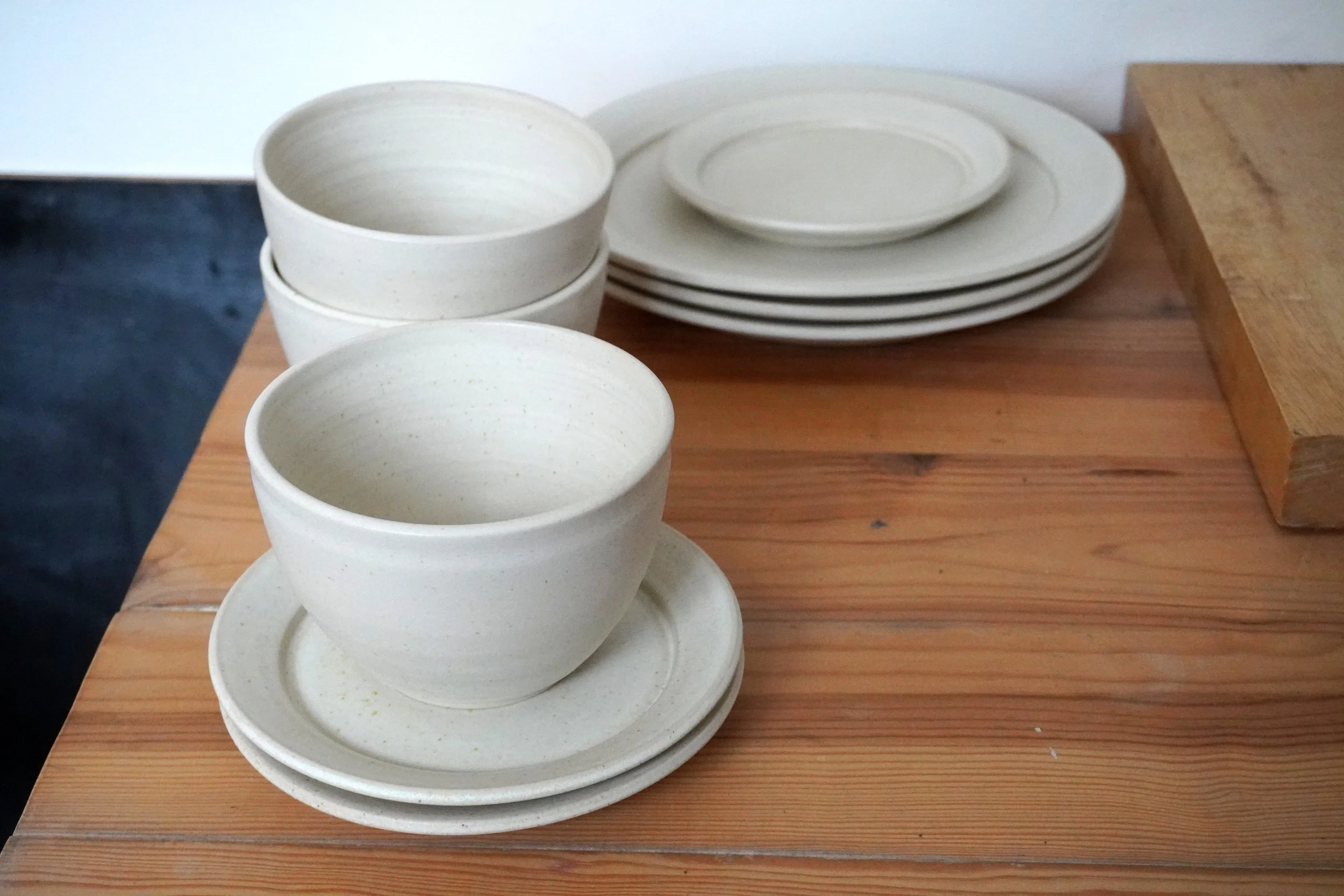 The parts of the dinner set stacked together, the tea plates, dinner plates and soup bowls