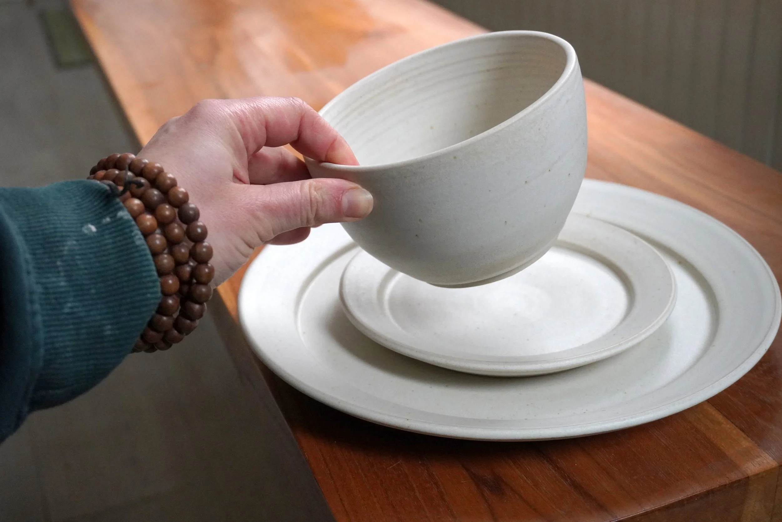 A hand holding the small soup bowl in the set for scale