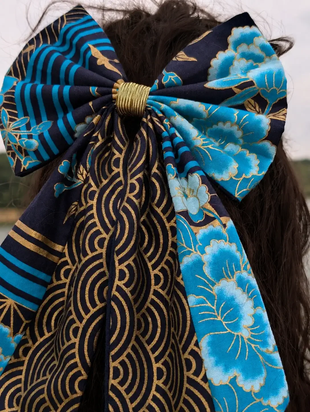 Détail du grand noeud Hana to Nami en tissu japonais bleu et or, avec fleurs et motifs Seigaiha dorés.