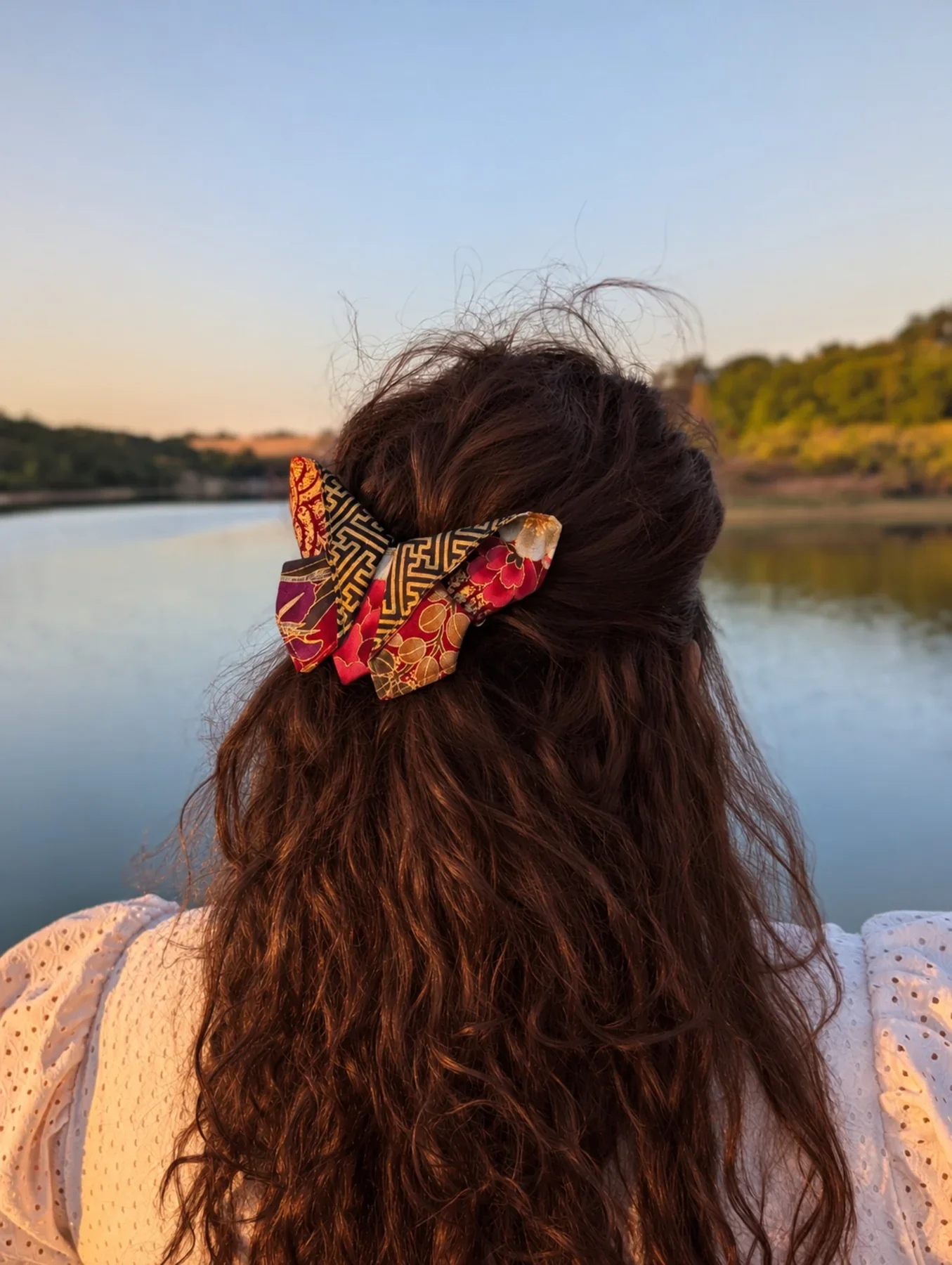 Grand papillon origami rouge noir et or porté de dos sur cheveux bruns.