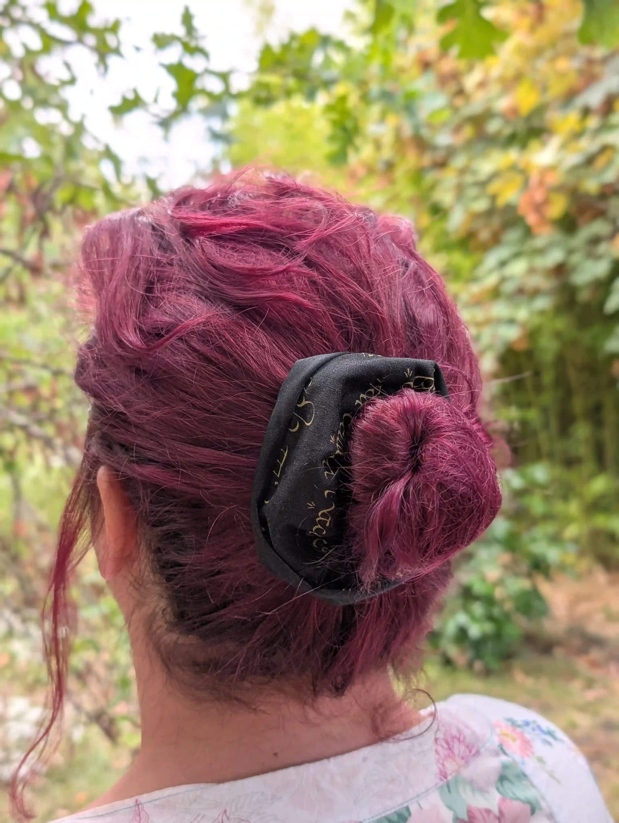 Grand chouchou Elfique noir et or porté autour d’un chignon, tissu à écriture dorée