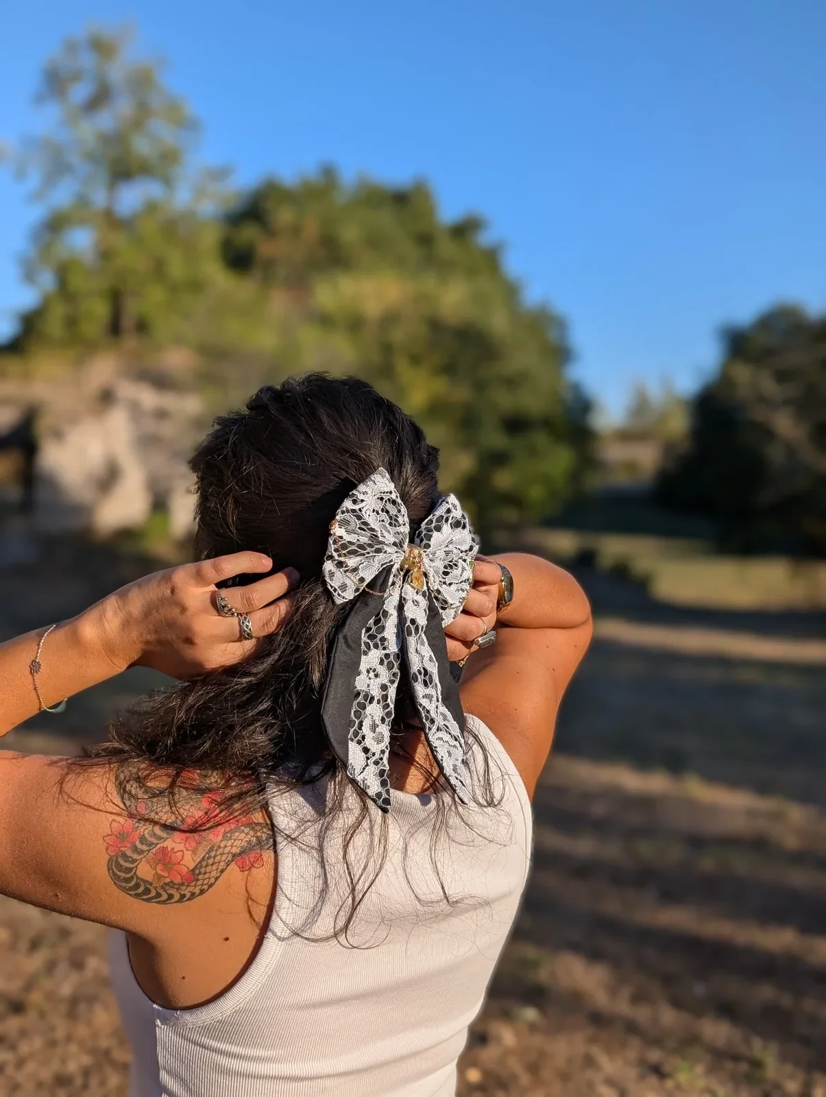 Noeud bijou en dentelle blanche à longues pointes, porté sur cheveux bruns, vue de côté.