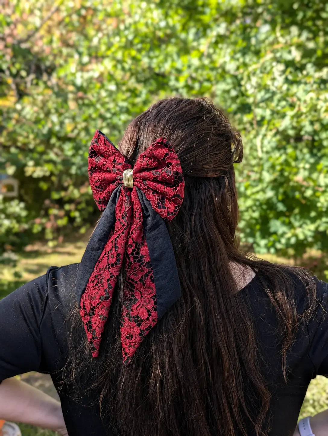 Grand noeud barrette en dentelle rouge profond et tissu noir, porté sur cheveux longs.