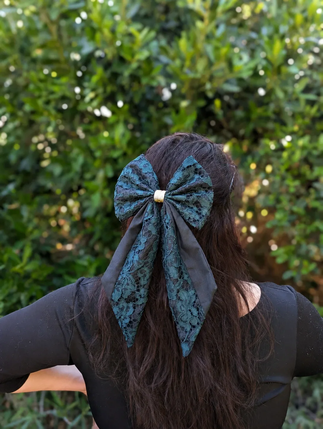 Grand noeud pour cheveux en dentelle vert émeraude et tissu noir, porté sur une demi-queue.