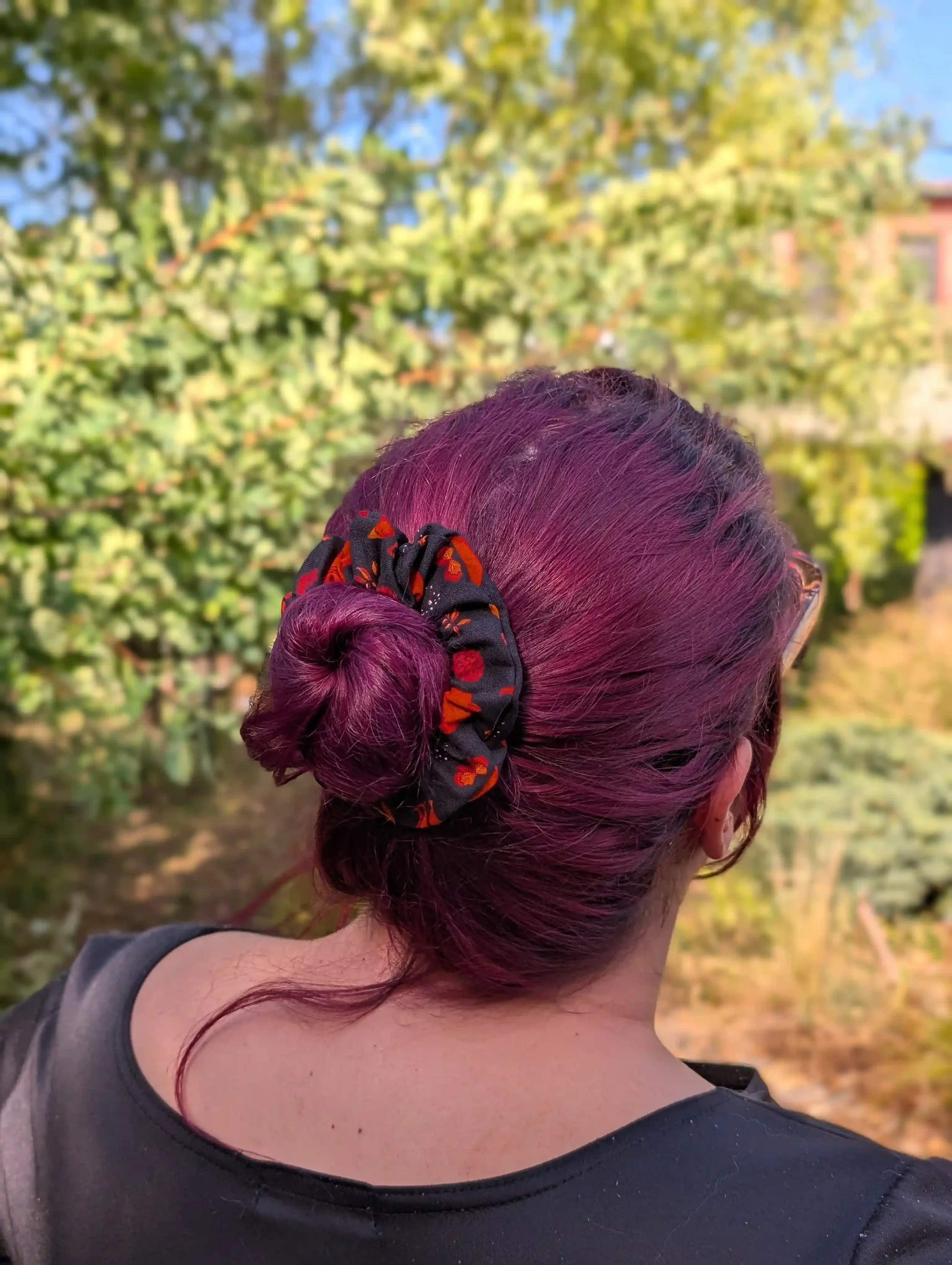 Petit chouchou Renards noir et rouille porté autour d’un chignon sur cheveux bordeaux