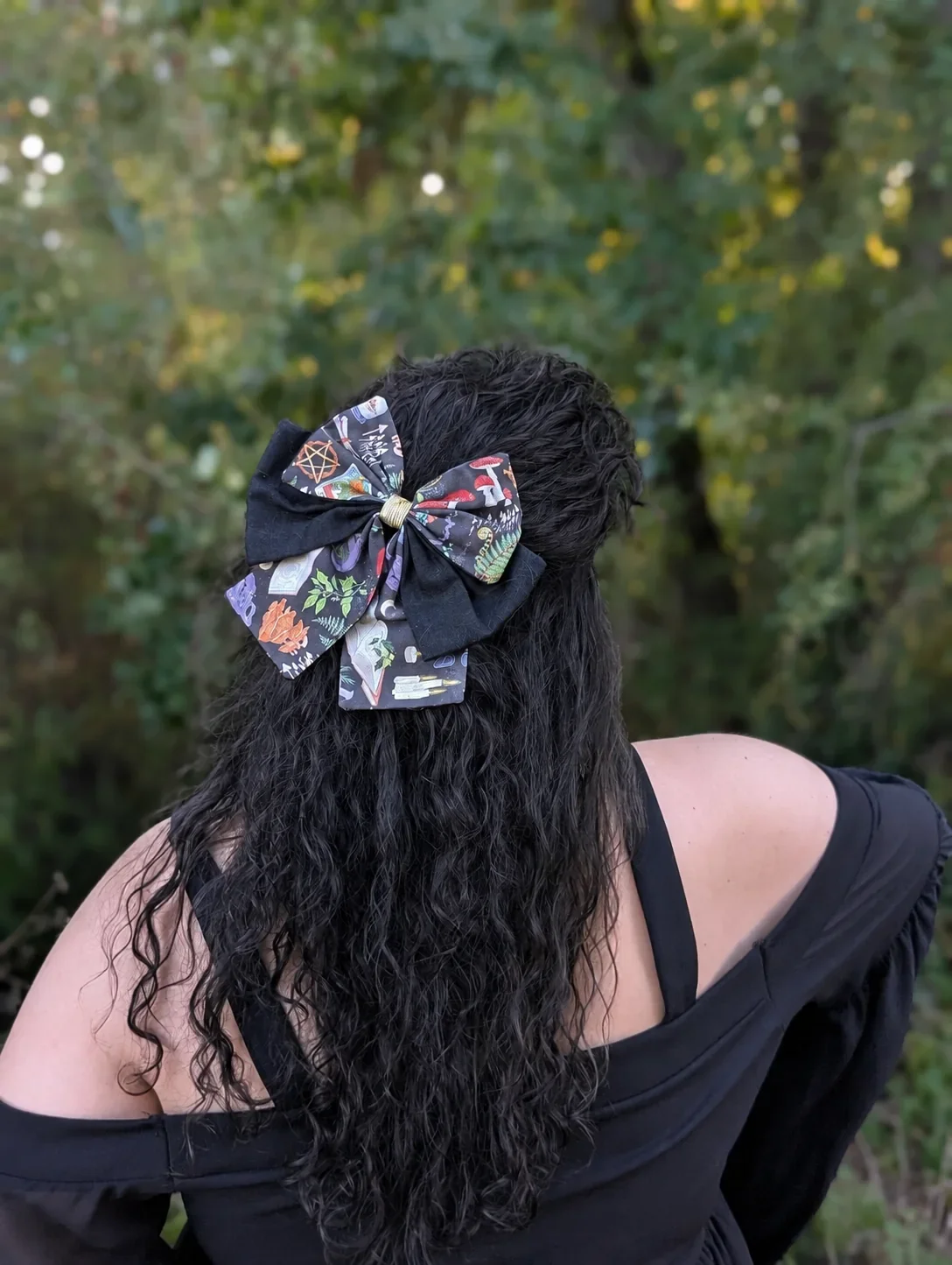 Nœud barrette Grimoire des bois sur cheveux noirs bouclés, vue de trois quarts des pointes imprimées.