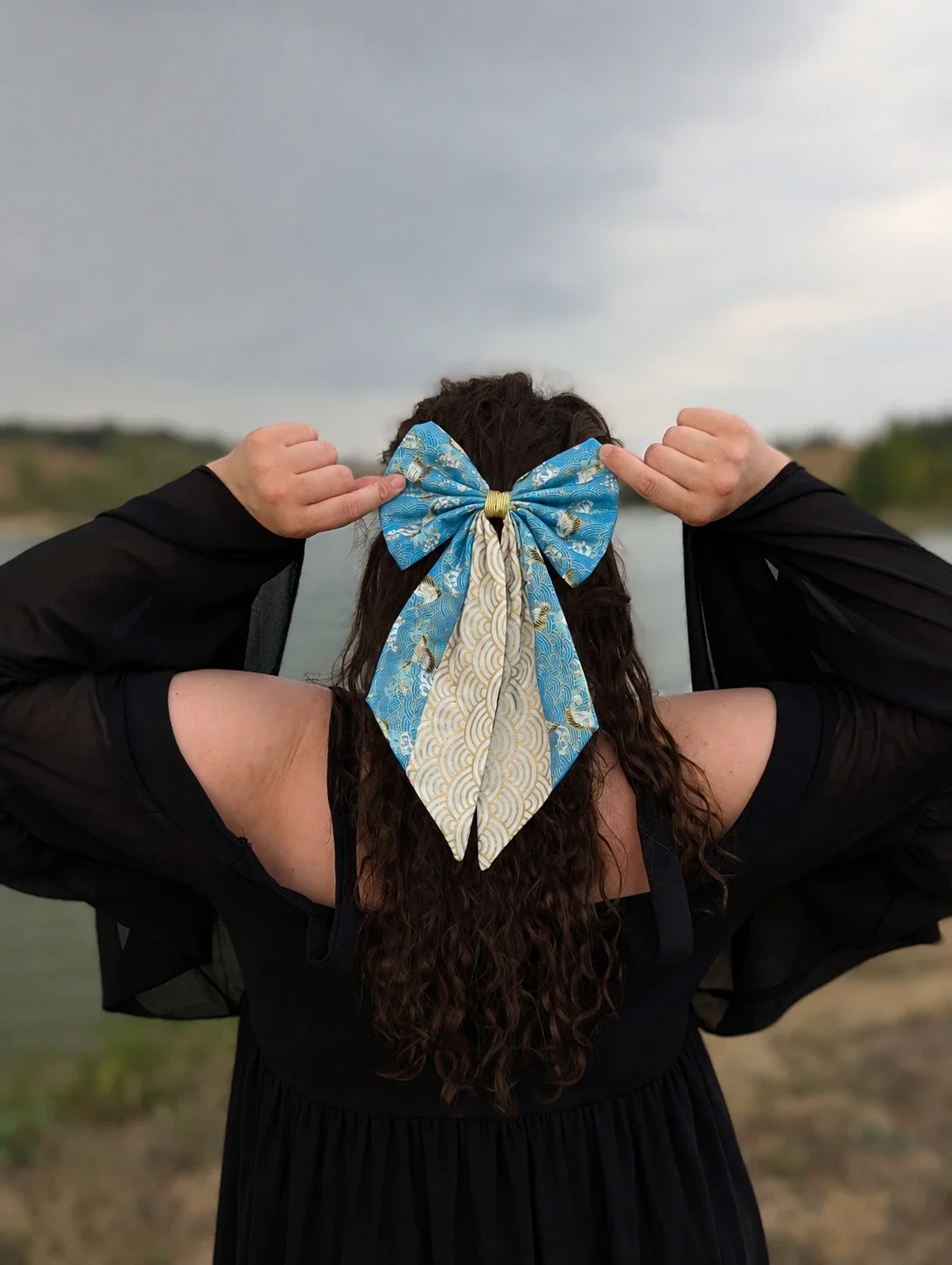 Nœud barrette Sora to Umi bleu, blanc et or porté sur une coiffure semi-attachée.