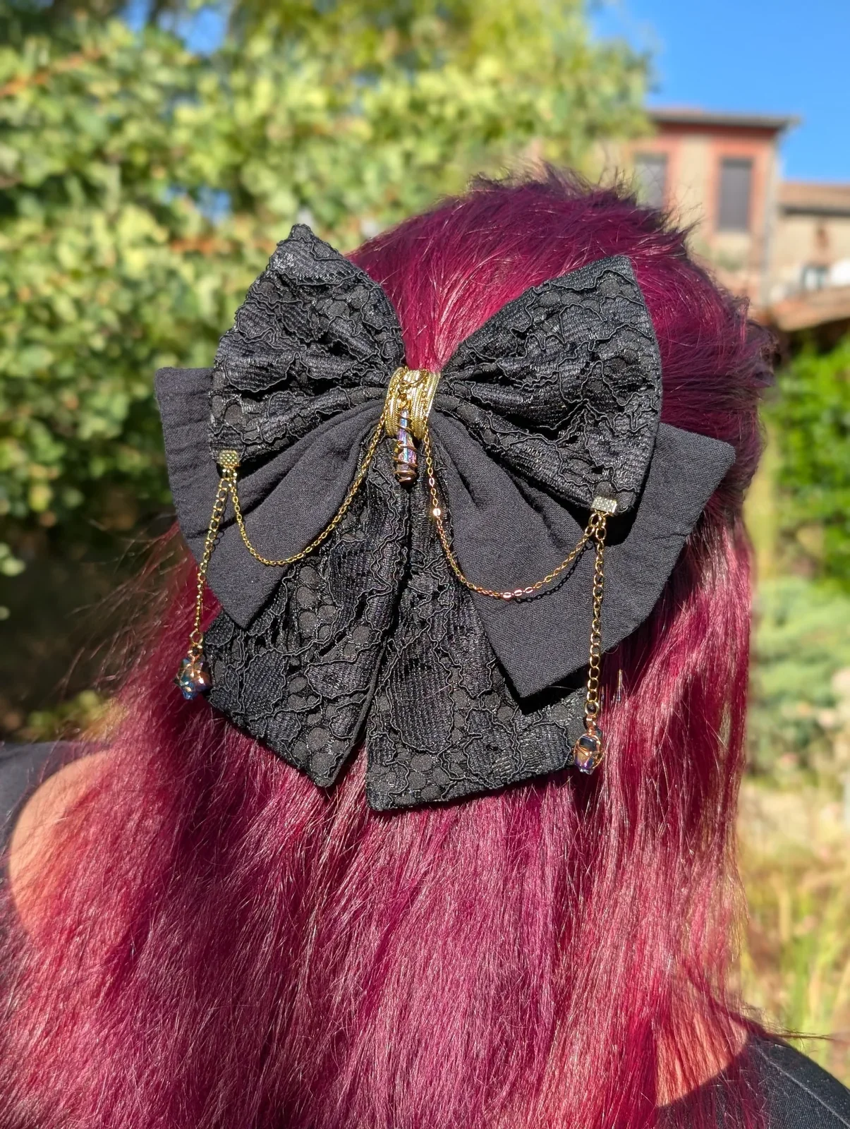 Noeud Dentelle noir sur cheveux roses, vue de trois quarts des chaînes et étoiles suspendues.