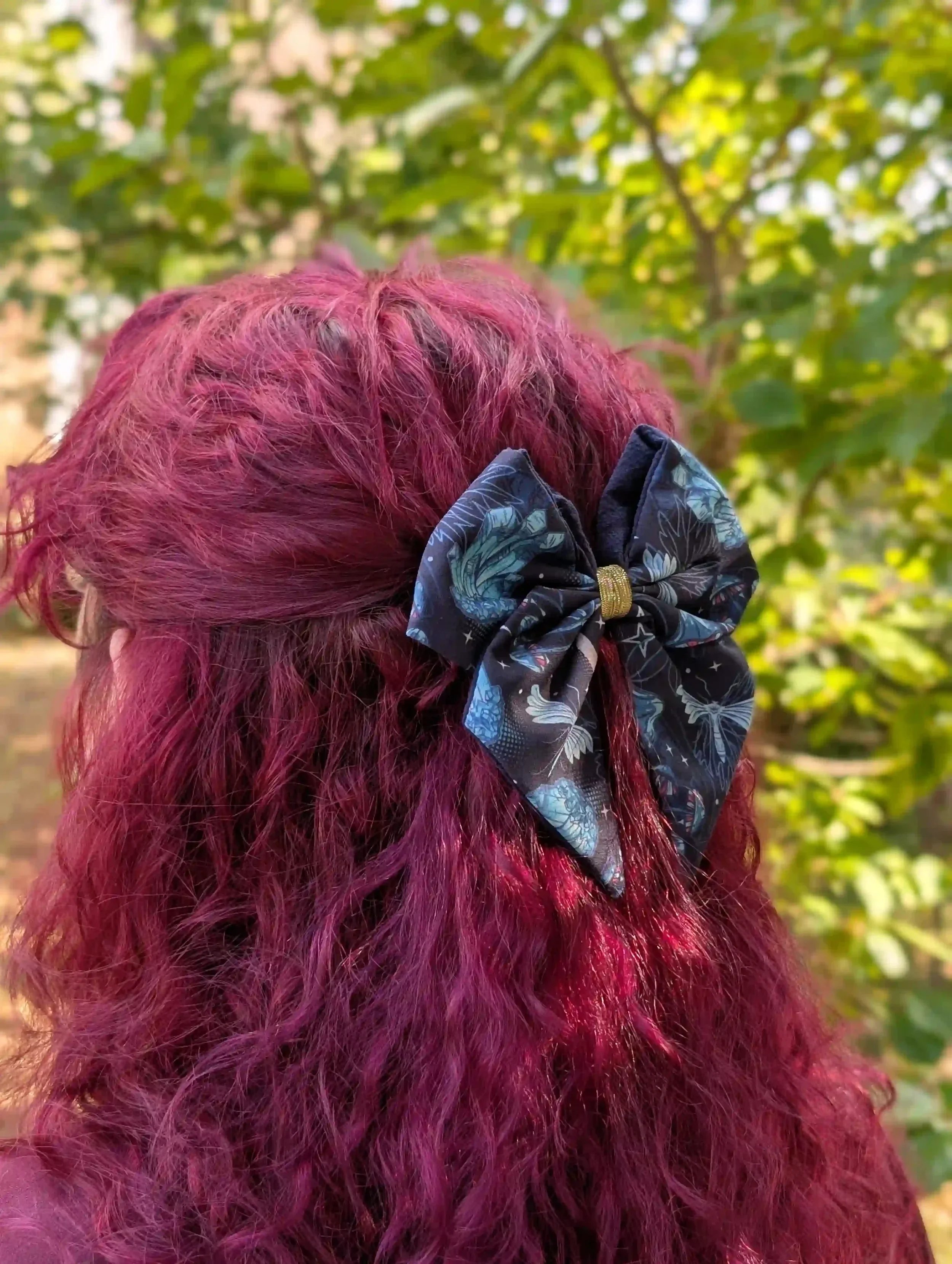 Barrette nœud Cristal noire et bleue portée dans les cheveux, vue de côté sur une coiffure semi-attachée.