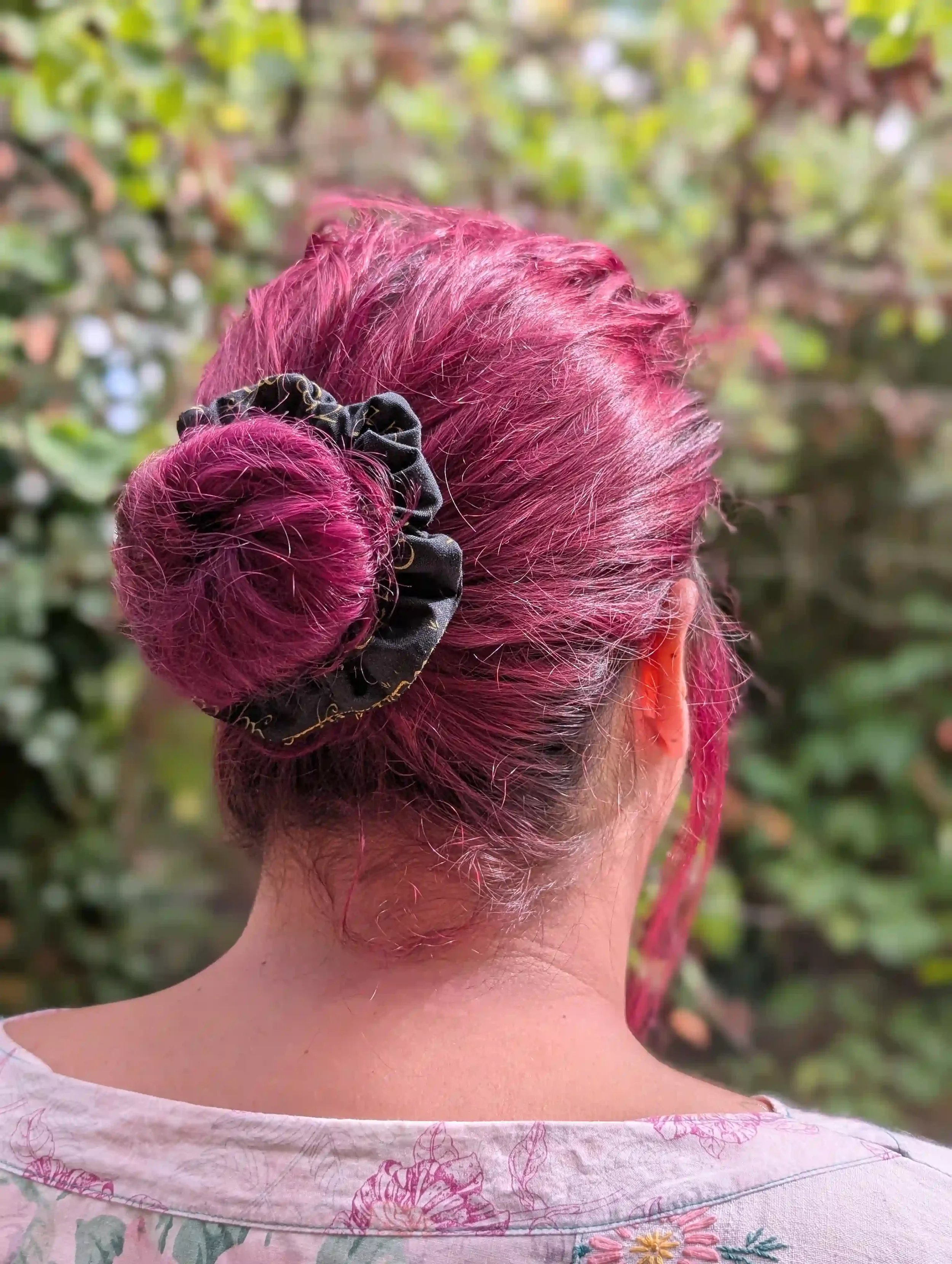 Petit chouchou Elfique noir et or porté autour d’un chignon bas sur cheveux roses