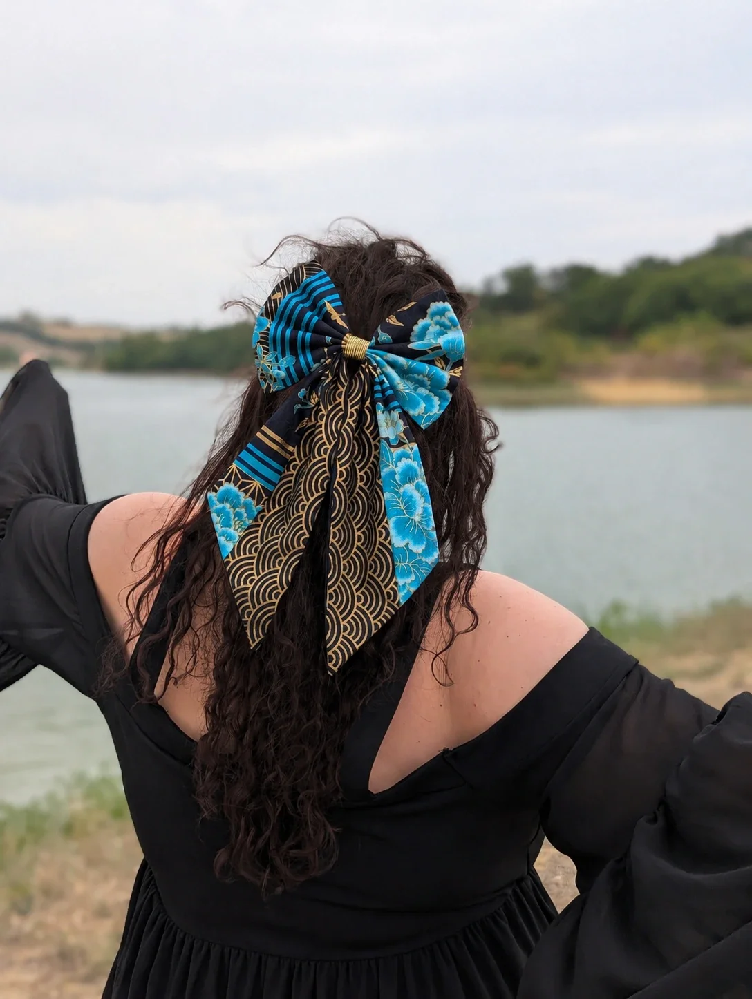 Très grand Nœud barrette Hana to Nami porté de dos sur cheveux bouclés, avec longs pans Seigaiha noirs et dorés.