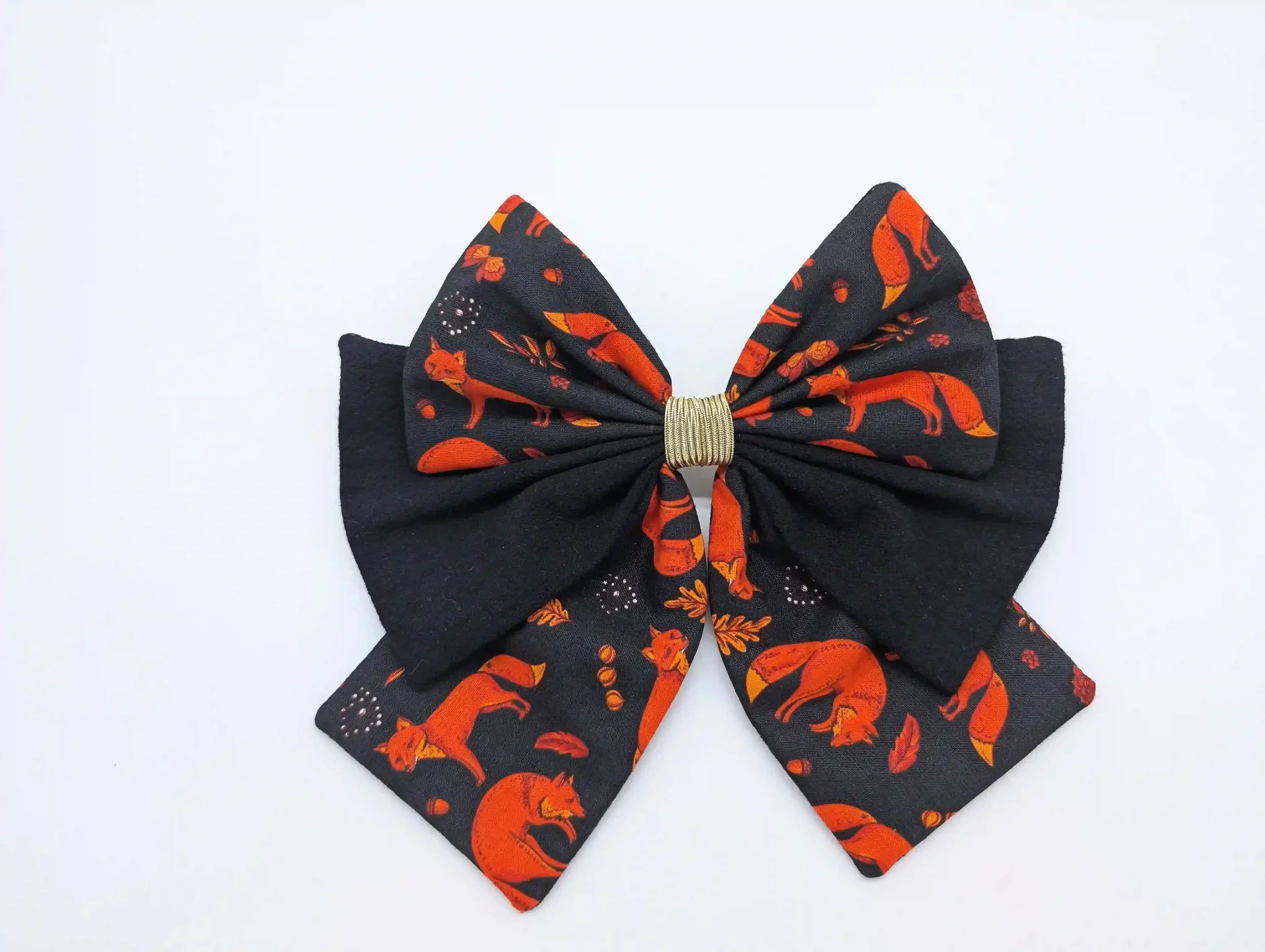 Nœud pour cheveux Renards taille M, en coton noir à motifs automnaux roux, présenté de face avec un centre doré.