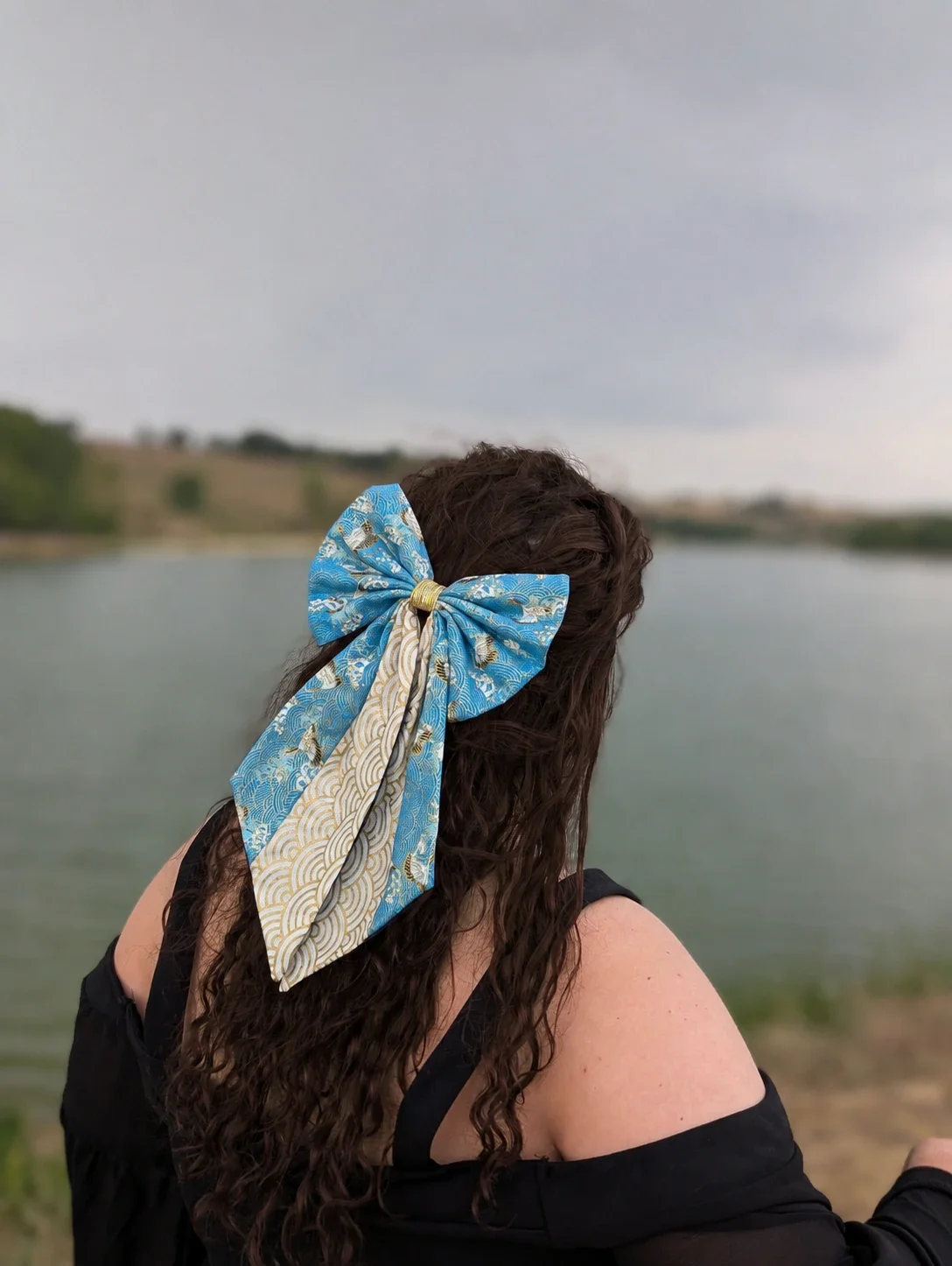 Grand nœud Sora to Umi bleu et doré porté sur cheveux longs au bord de l’eau.