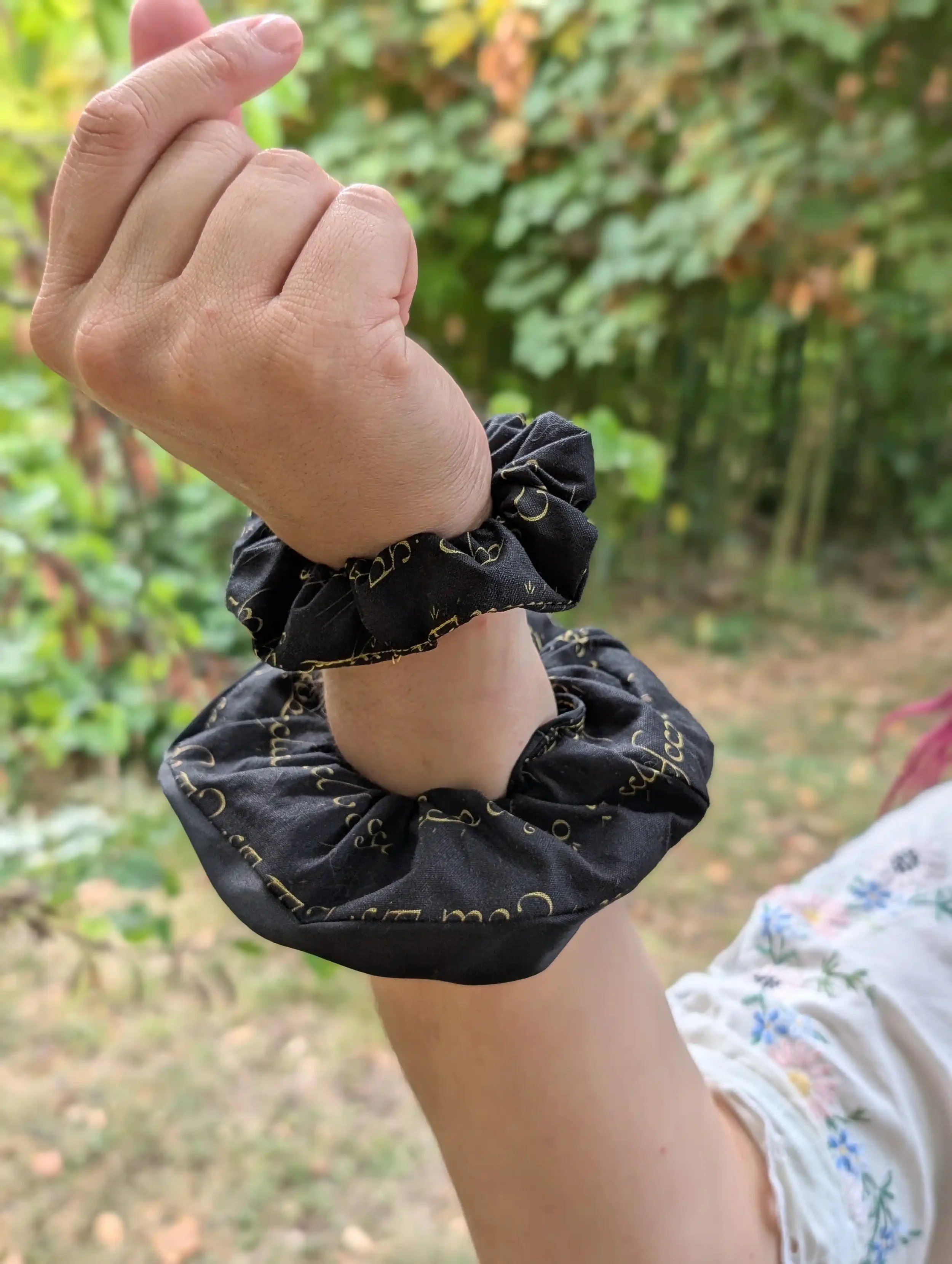 Petit et grand chouchous Elfique noir et or portés au poignet pour comparer les deux tailles