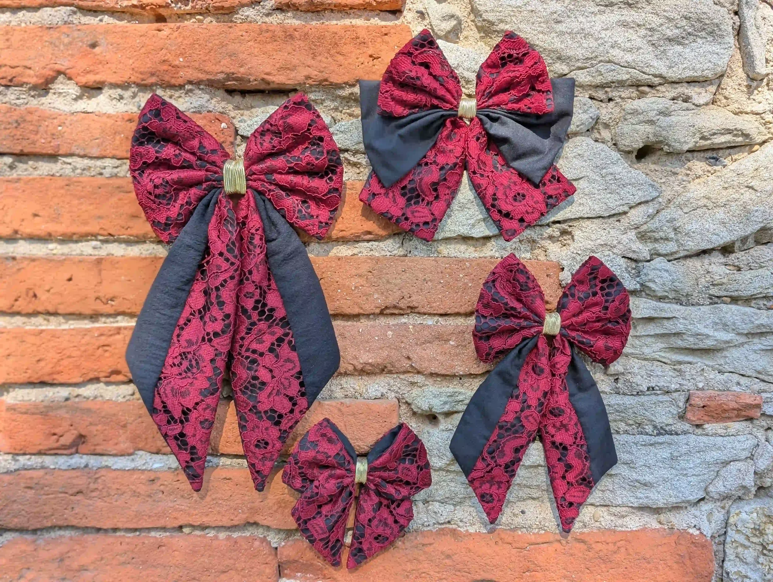 Collection de nœuds pour cheveux en dentelle rouge profond et tissu noir, présentés en plusieurs tailles.