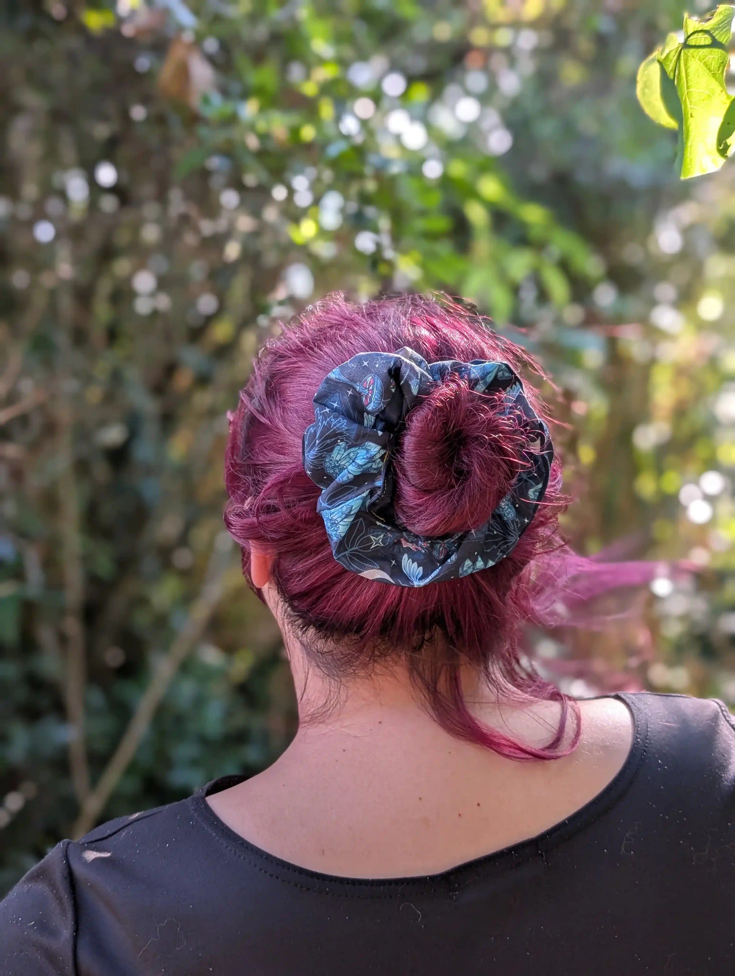 Grand chouchou Cristal noir et bleu porté autour d’un chignon sur cheveux colorés.