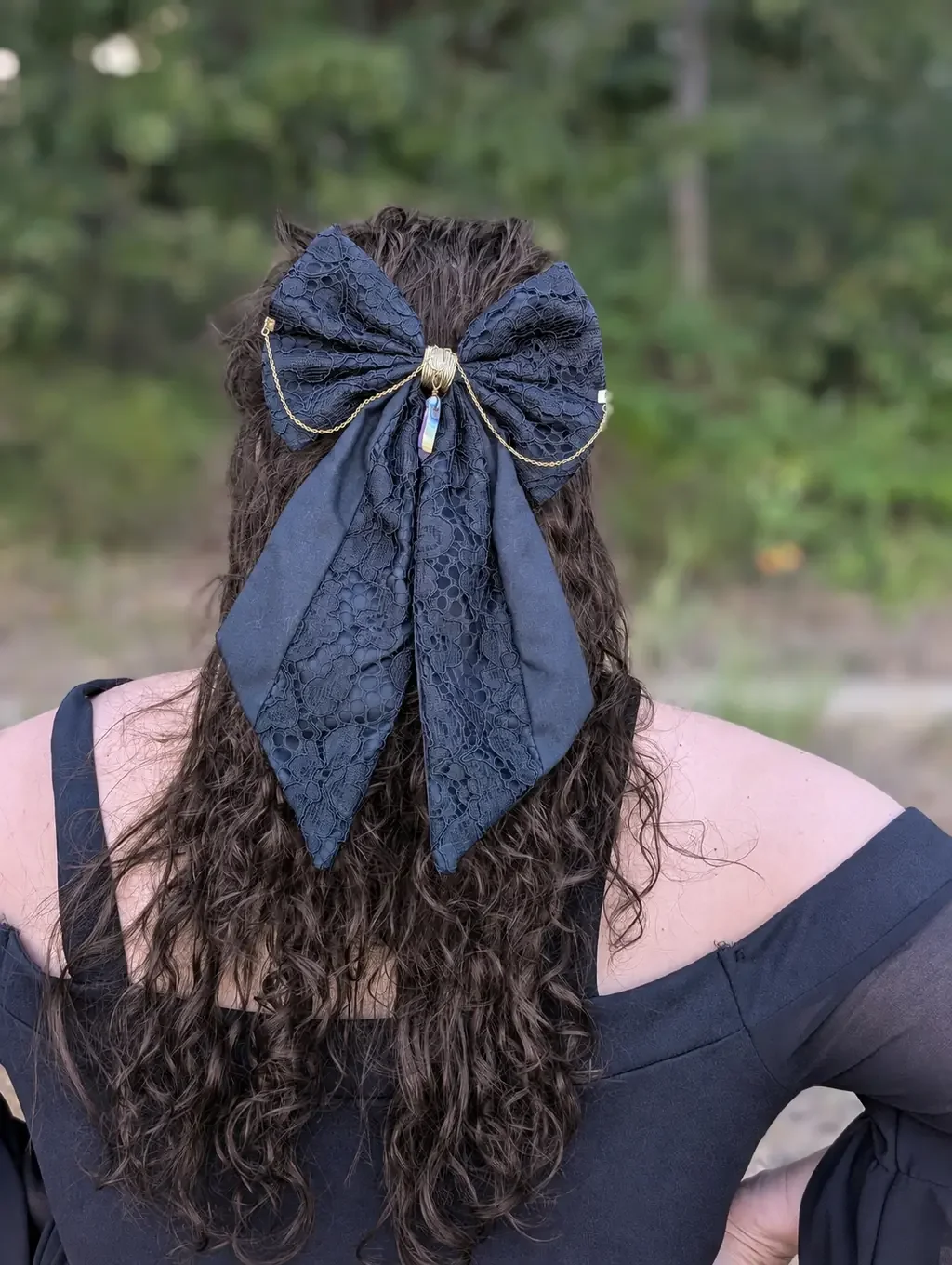 Noeud bijou xl en dentelle noire sur cheveux bruns bouclés, vue de dos en extérieur