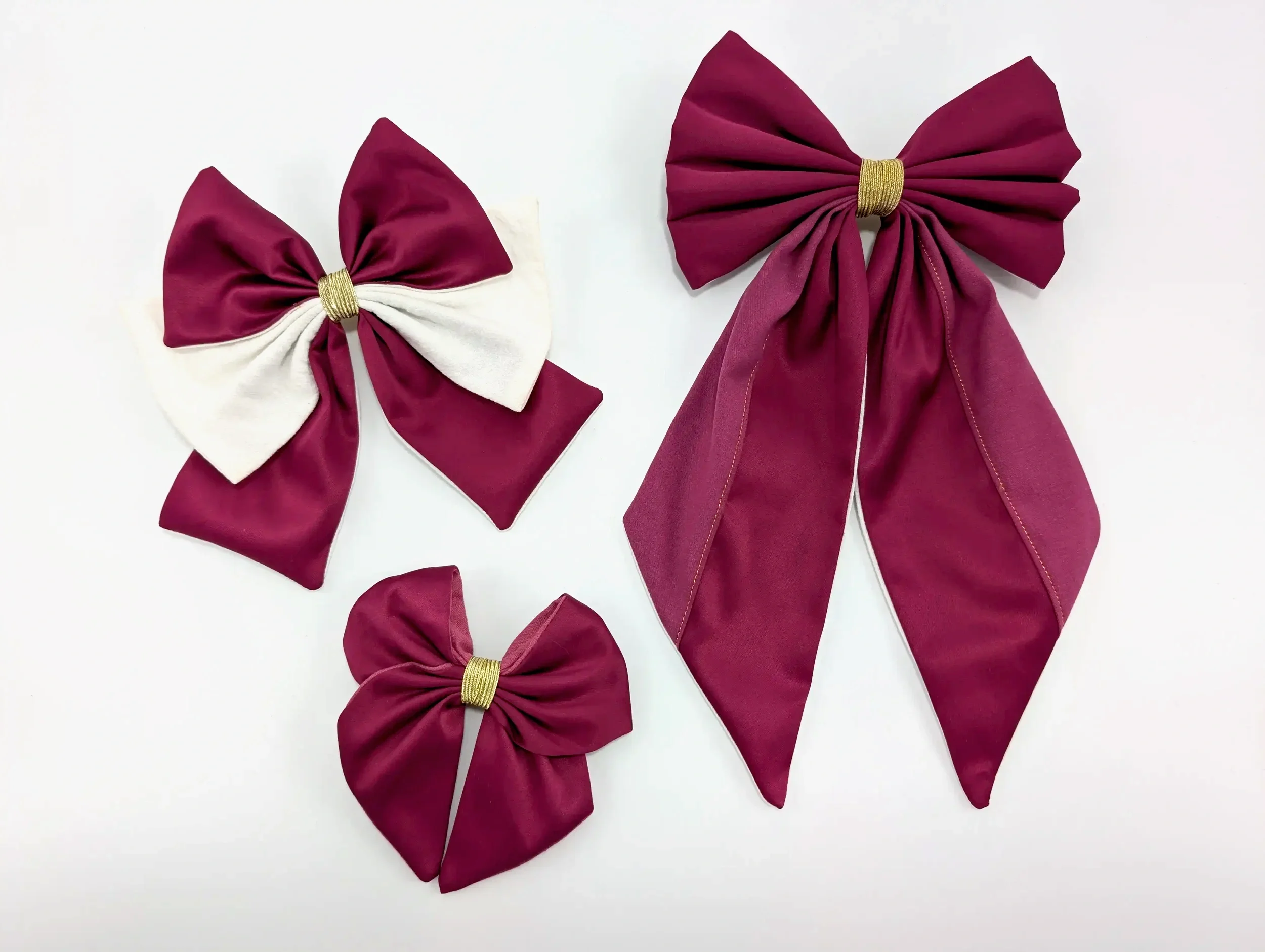 Trois barrettes nœuds pour cheveux rose vif de différentes tailles, dont un modèle bicolore blanc et rose vif.
