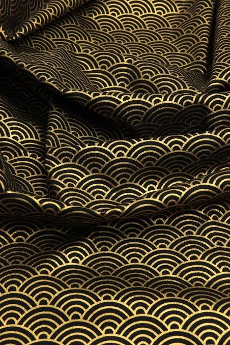 Gros plan sur un tissu japonais noir aux vagues Seigaiha dorées.
