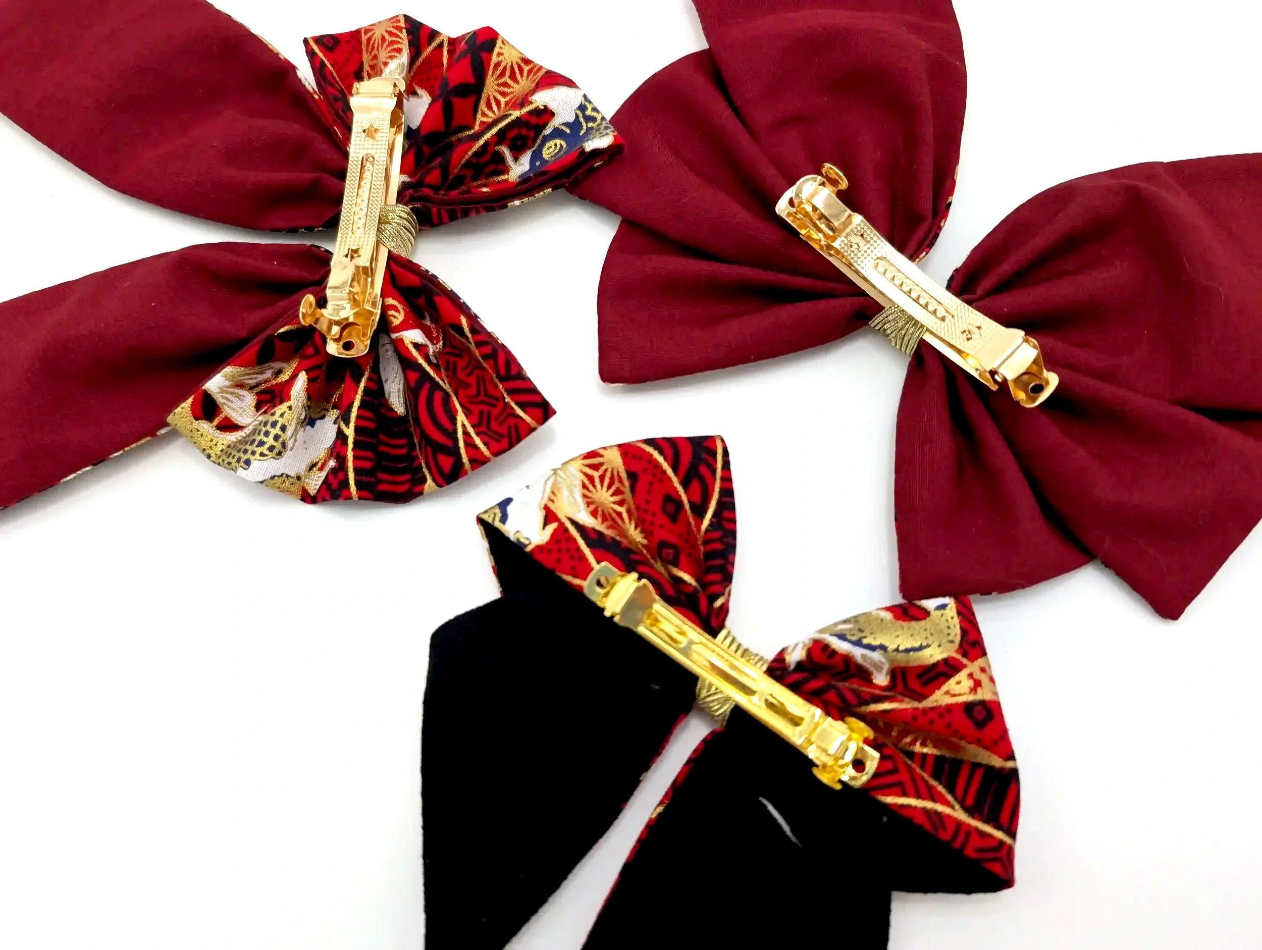 Gros plan sur le mécanisme de la barrette métallique dorée des nœuds cheveux Koï rouge, tissu Sayagata bordeaux et or à motif carpes japonaises.