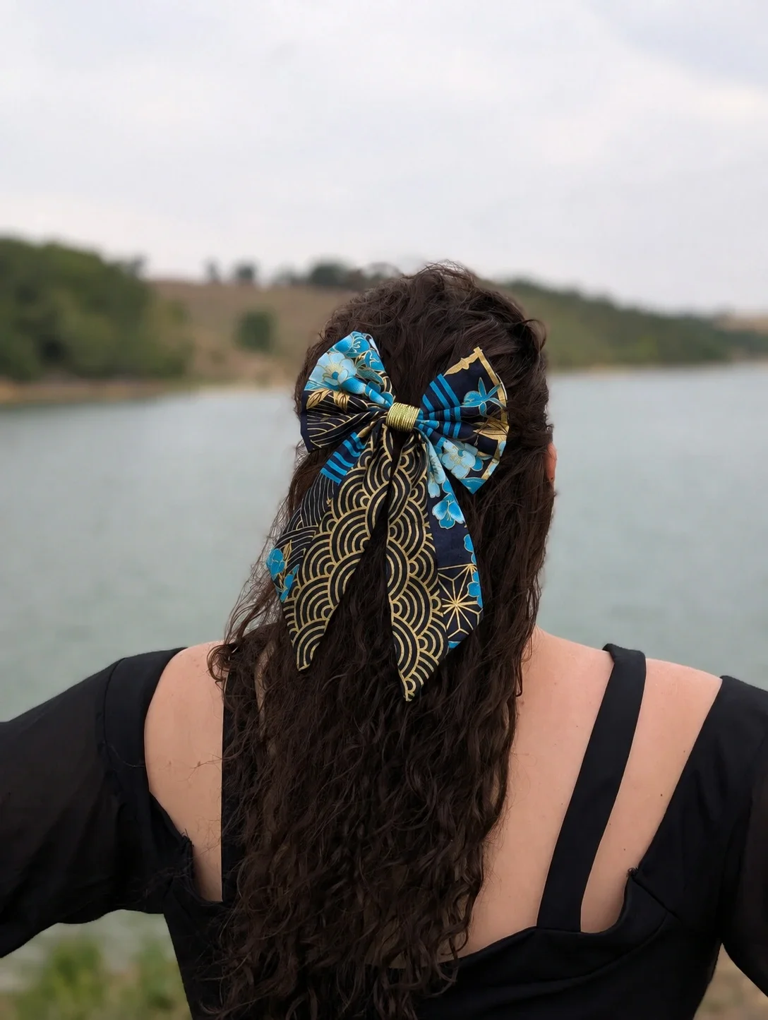 Nœud barrette Hana to Nami à fleurs bleues et vagues Seigaiha dorées porté de dos sur cheveux longs.