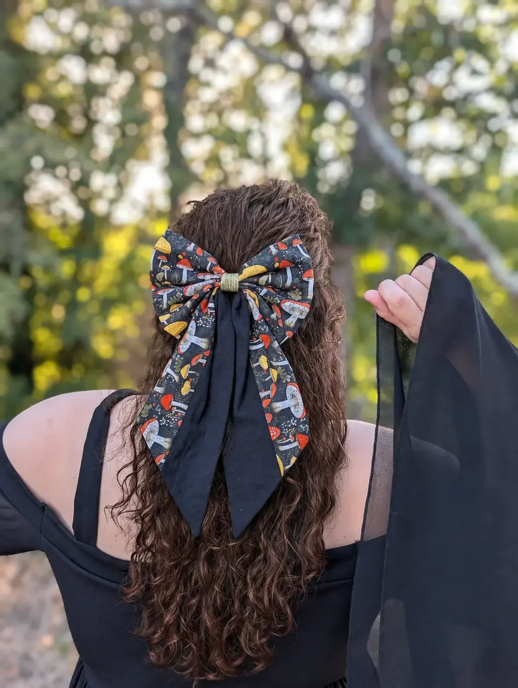 Nœud Mycélia à longues pointes noires et motifs champignons porté de dos sur cheveux bruns.