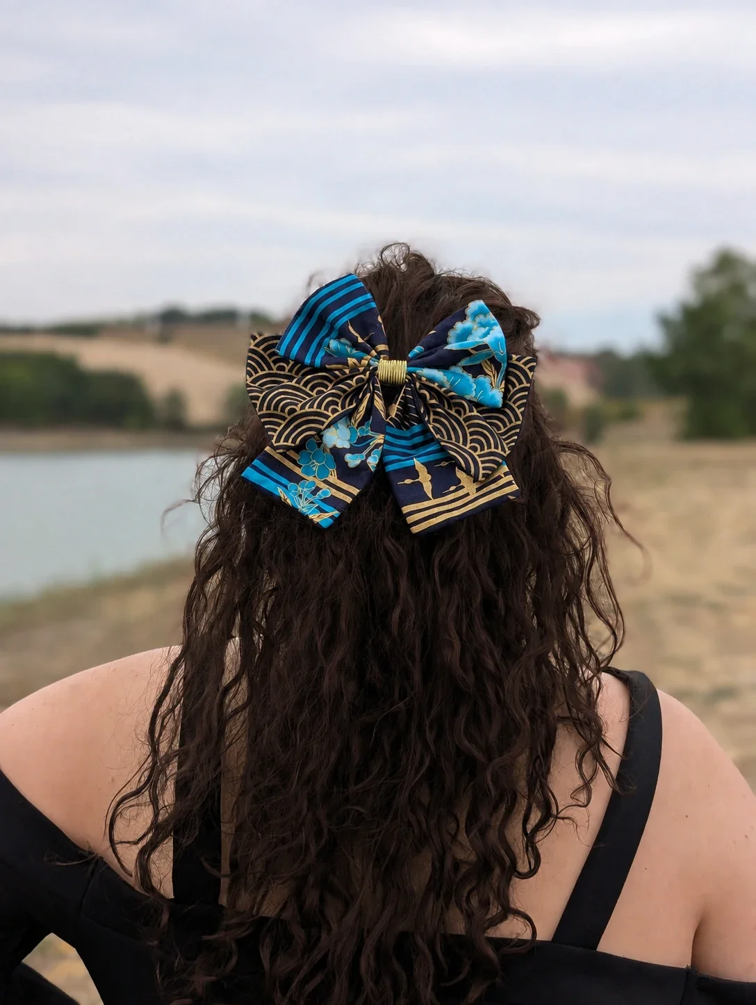 Noeud pour cheveux Hana to Nami bleu marine, turquoise et or porté sur une coiffure semi-attachée.